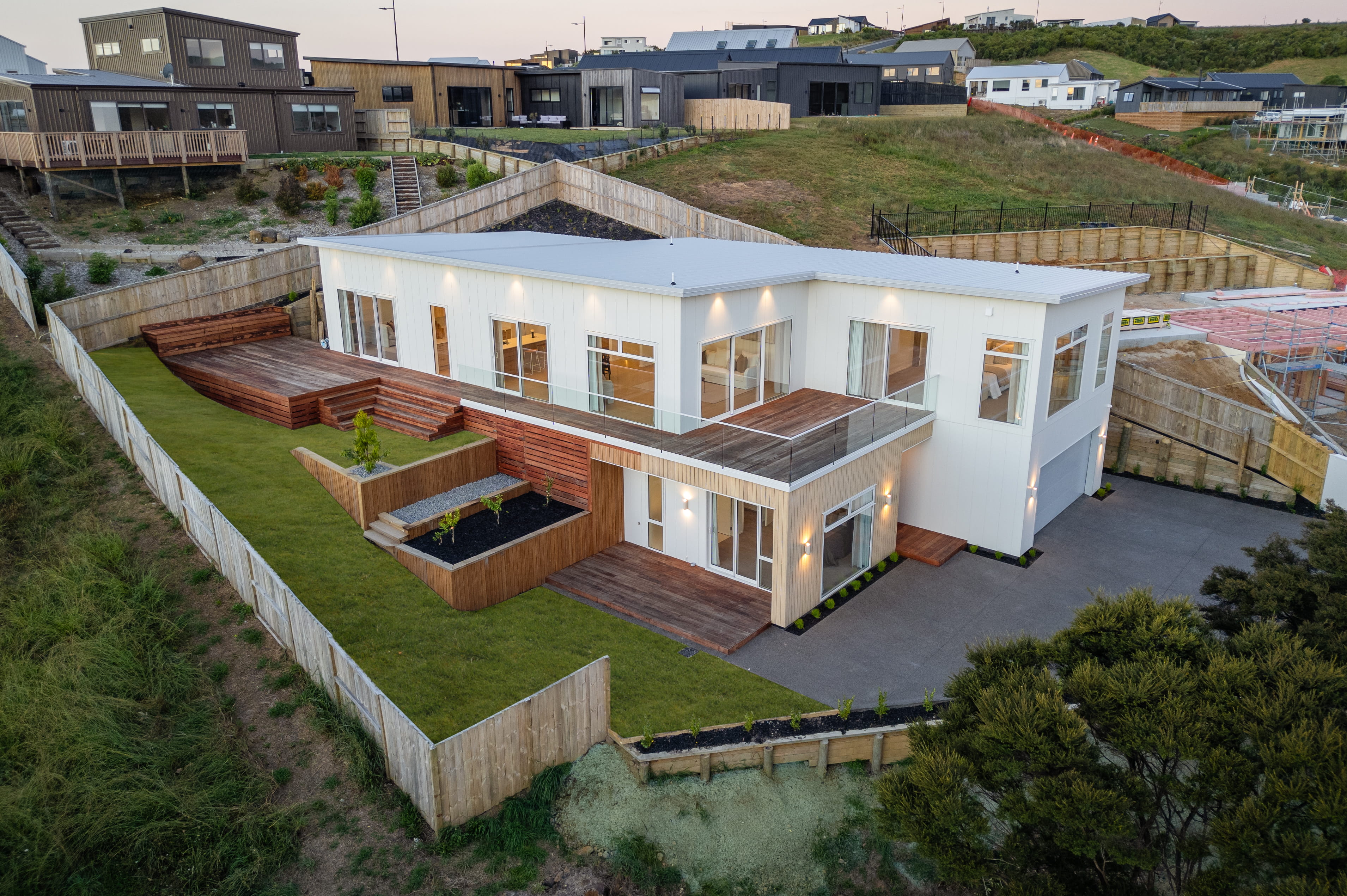 Two storey home with white cladding and built on a sloping site with mono pitch roof