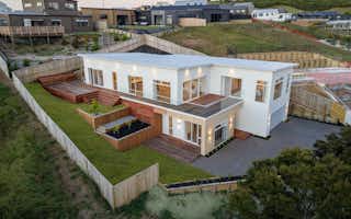 Two storey home with white cladding and built on a sloping site with mono pitch roof