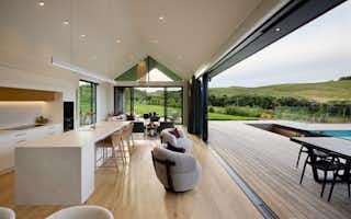 Open-plan kitchen and living area with vaulted ceiling and seamless indoor–outdoor flow to pool and decking.