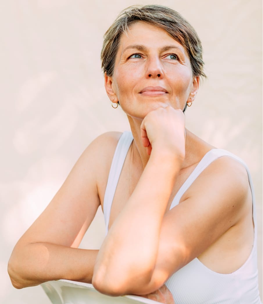Woman looking serene looking upward with her chin resting on her hand.