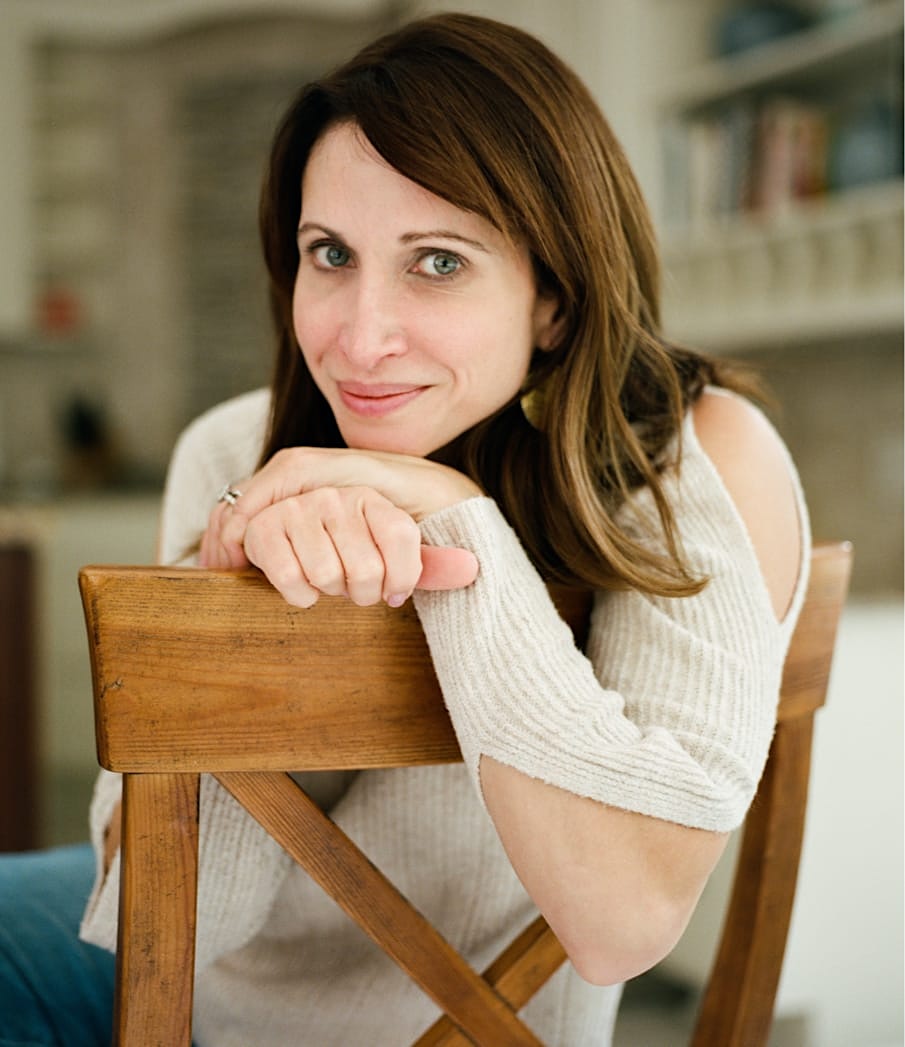 Woman leaning on the back of a chair smiling.