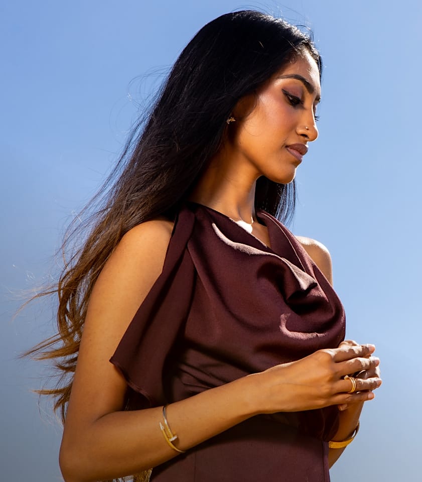 Dr. Srinivasa in a burgundy dress, face in profile, looking downward.