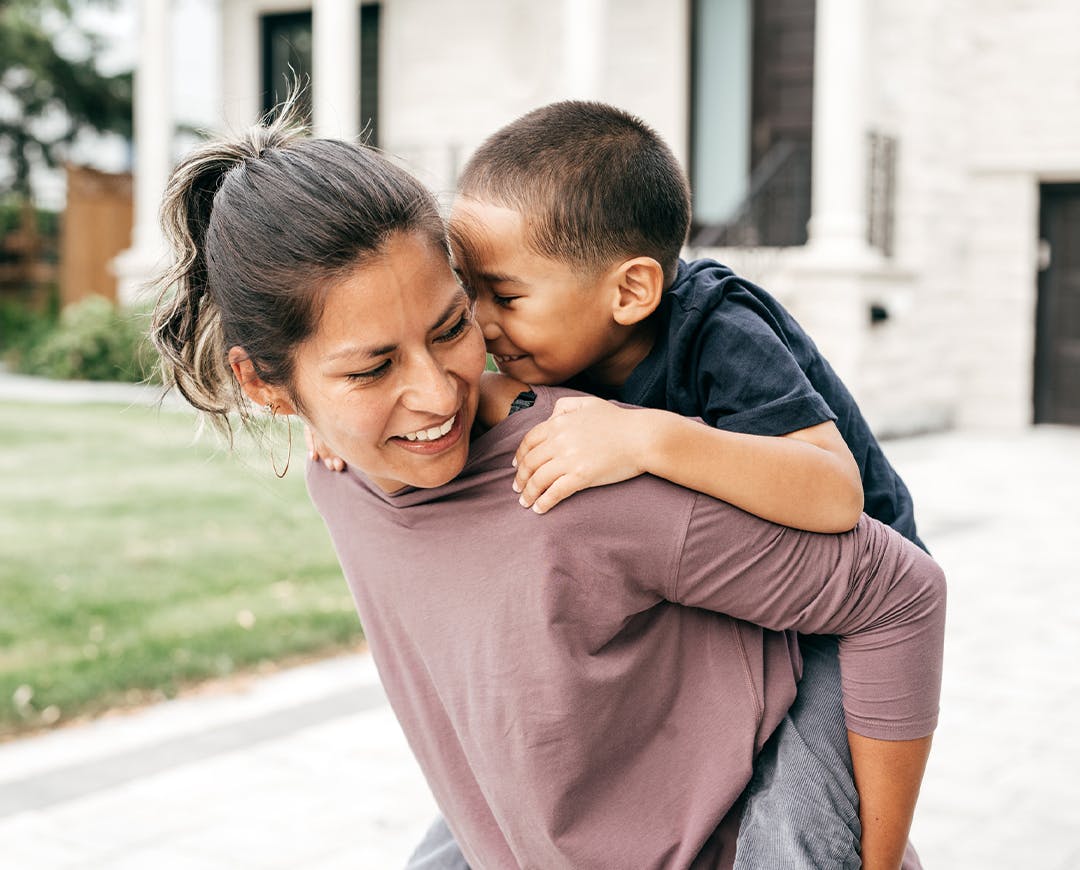 woman giving a kid a piggy back ride