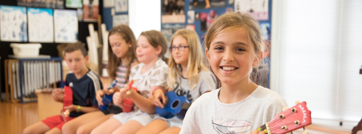 Children playing ukeleles in a classroom