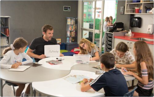 Teacher at desk with students