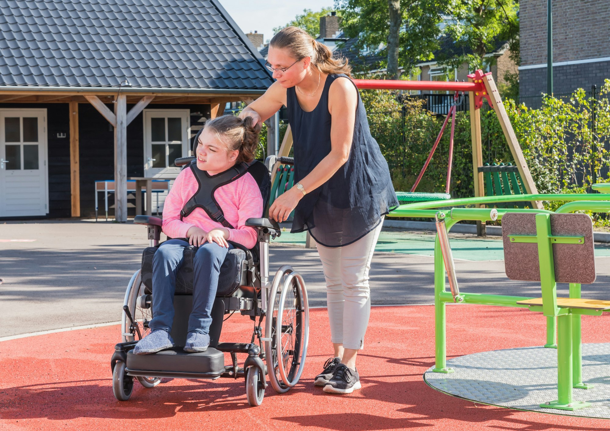 Student in a wheelchair in the playground accompanied by a teacher or carer