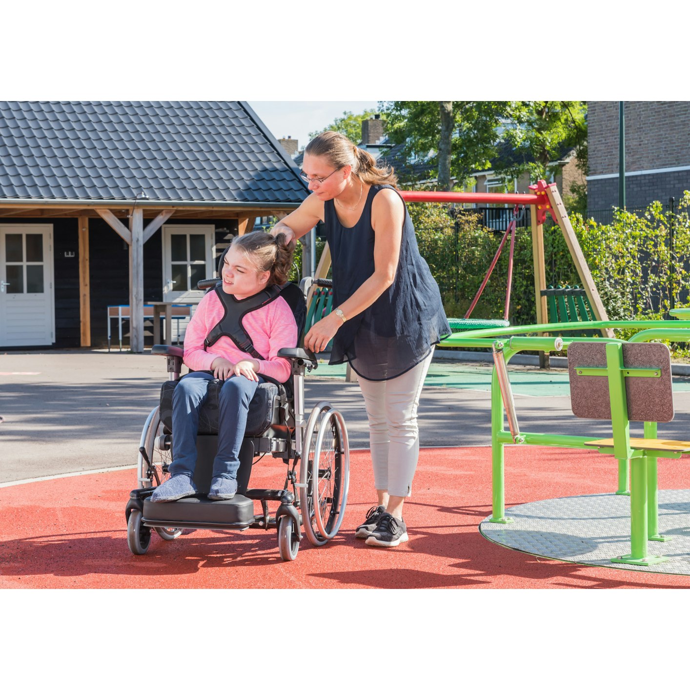 Student in a wheelchair in the playground accompanied by a teacher or carer