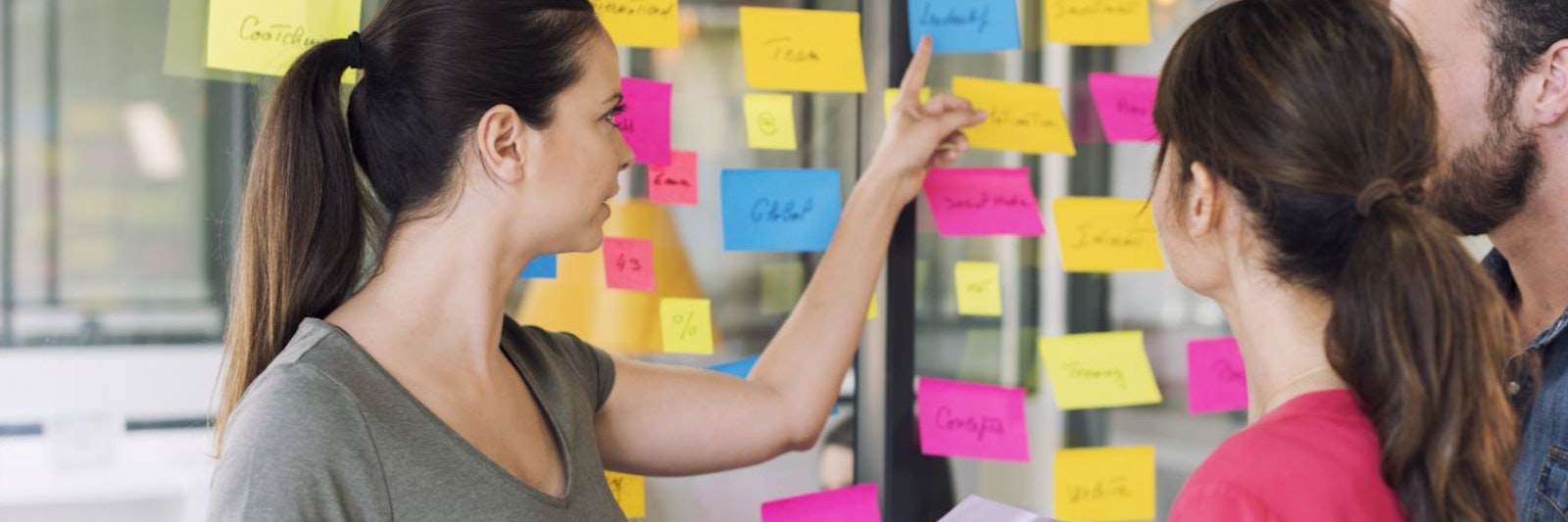 People pointing at sticky notes on a window