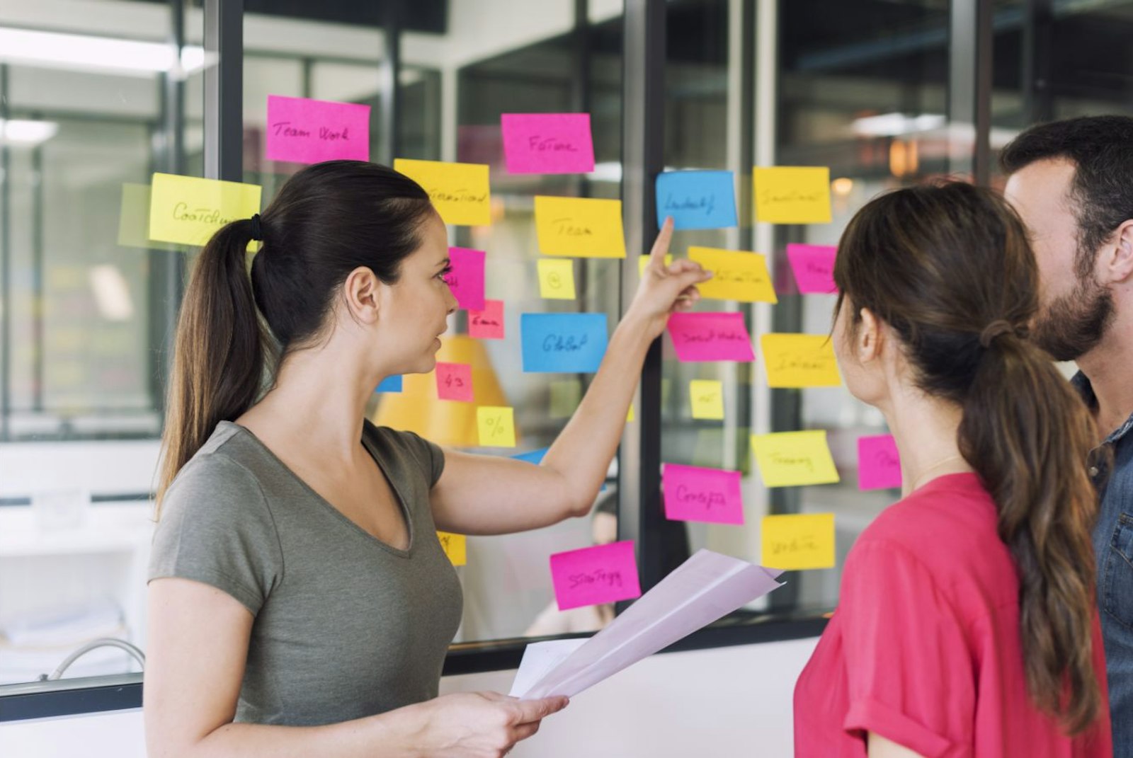 People pointing at sticky notes on a window