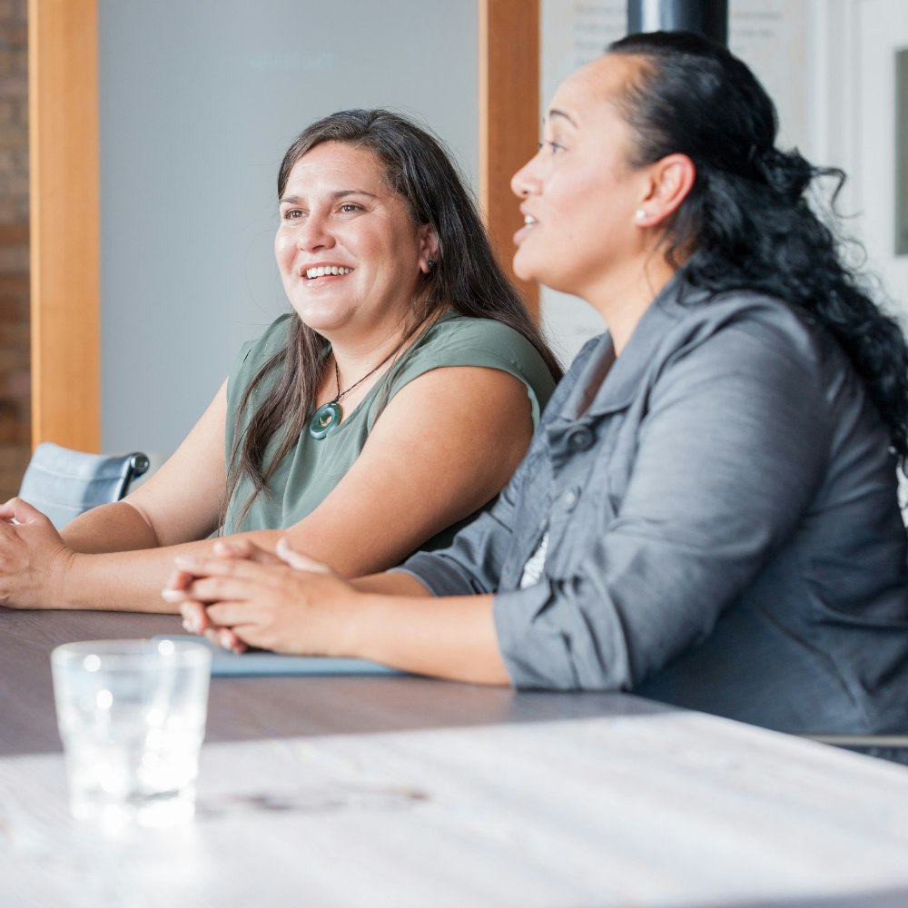 Two women sitting side by side at a table