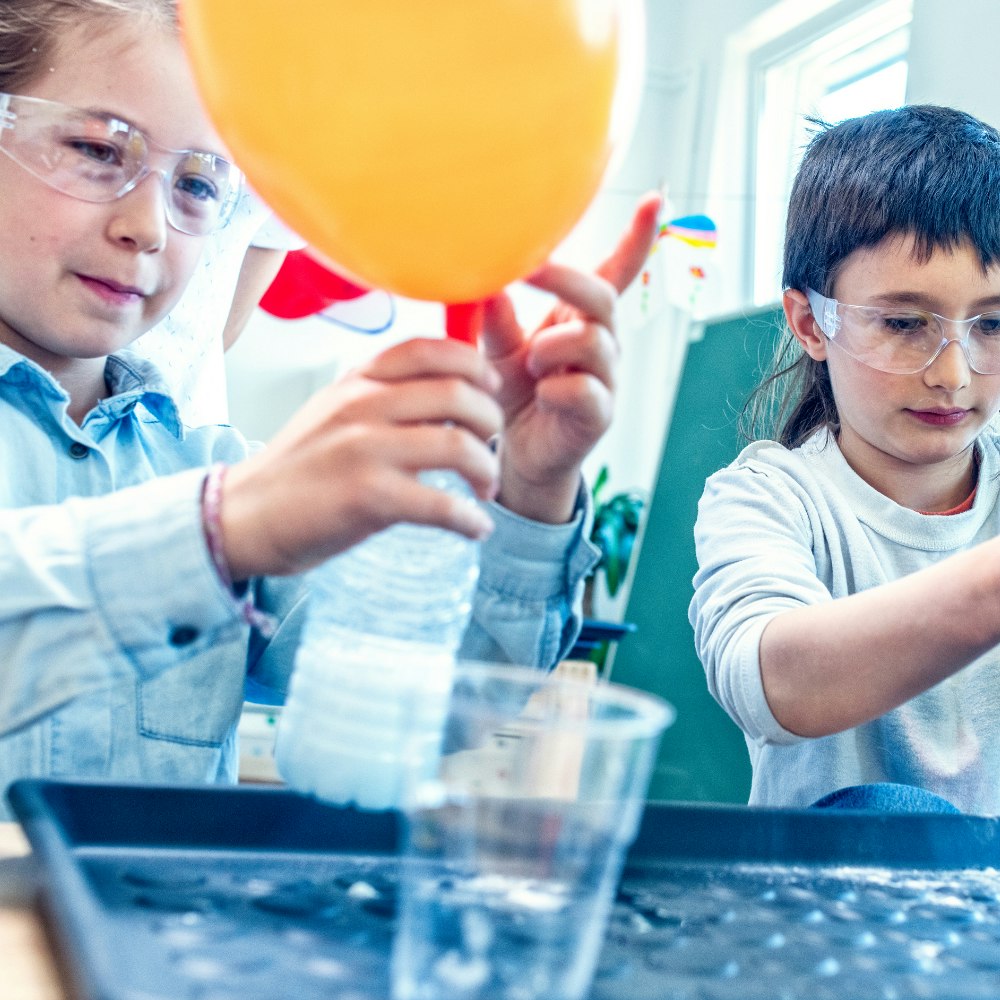 Two students doing a science experience with balloons and plastic bottles