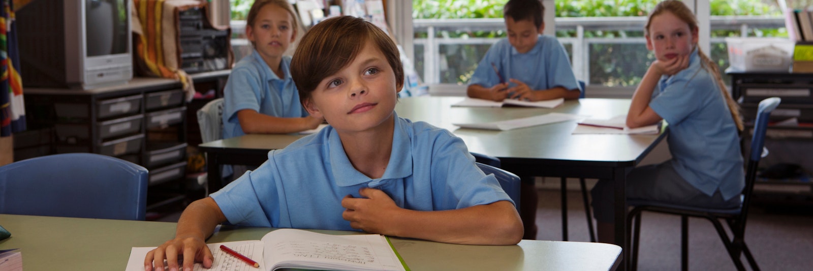 Boy sitting in classroom with book in front of him
