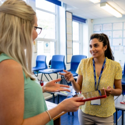 Two teachers standing in a classroom talking