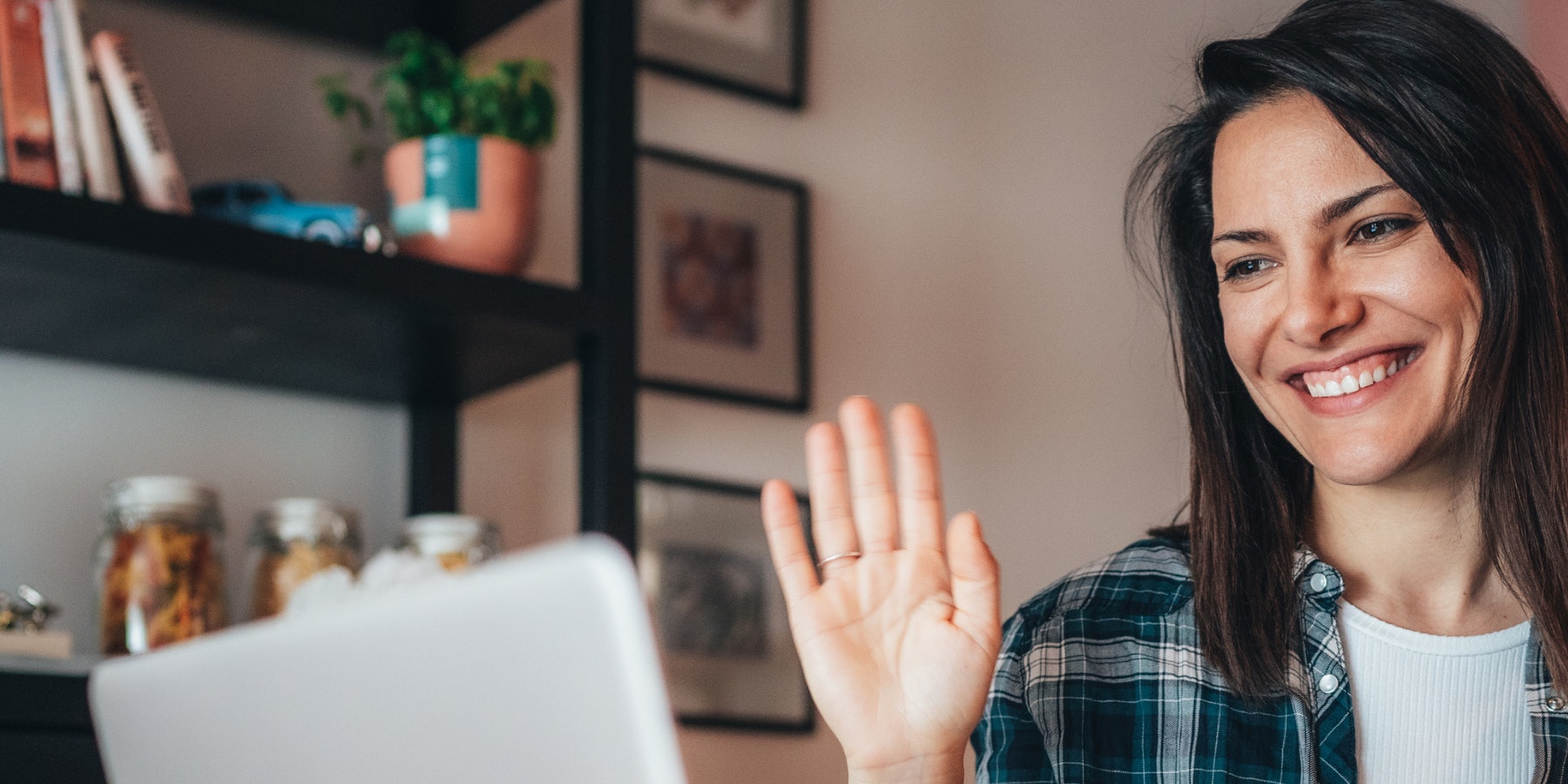 Woman waving at a computer screen