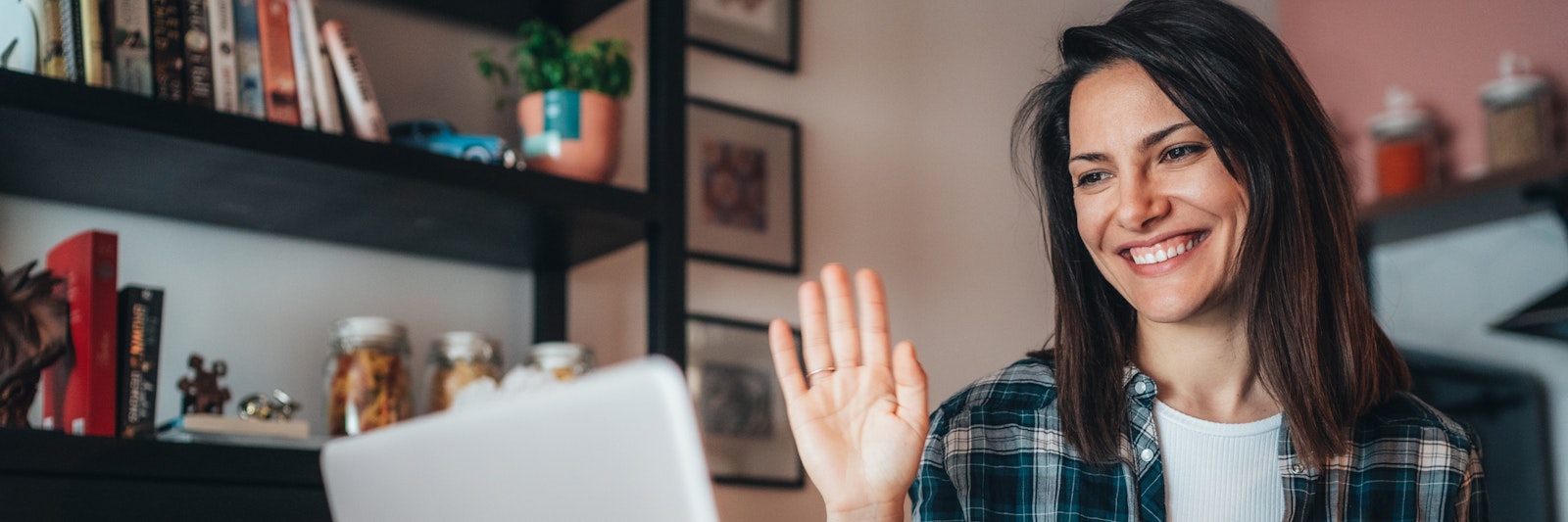 Woman waving at a computer screen