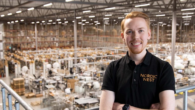 Medarbetare på Nordic Nest står framför en stor lager- och produktionsmiljö.
