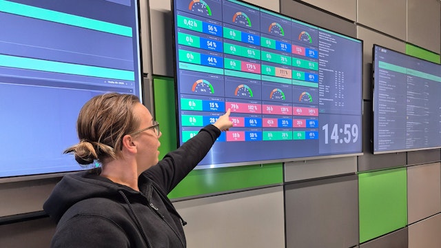 Person på Luni Metall pekar på en digital tavla med nyckeltal, mätare och produktionsdata.