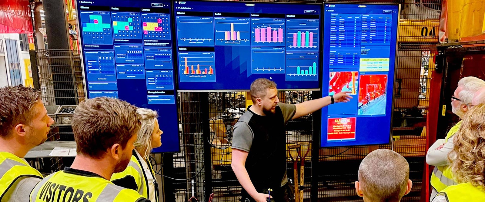 Group of visitors attending a walkthrough at digital management boards in Väderstad’s production environment.