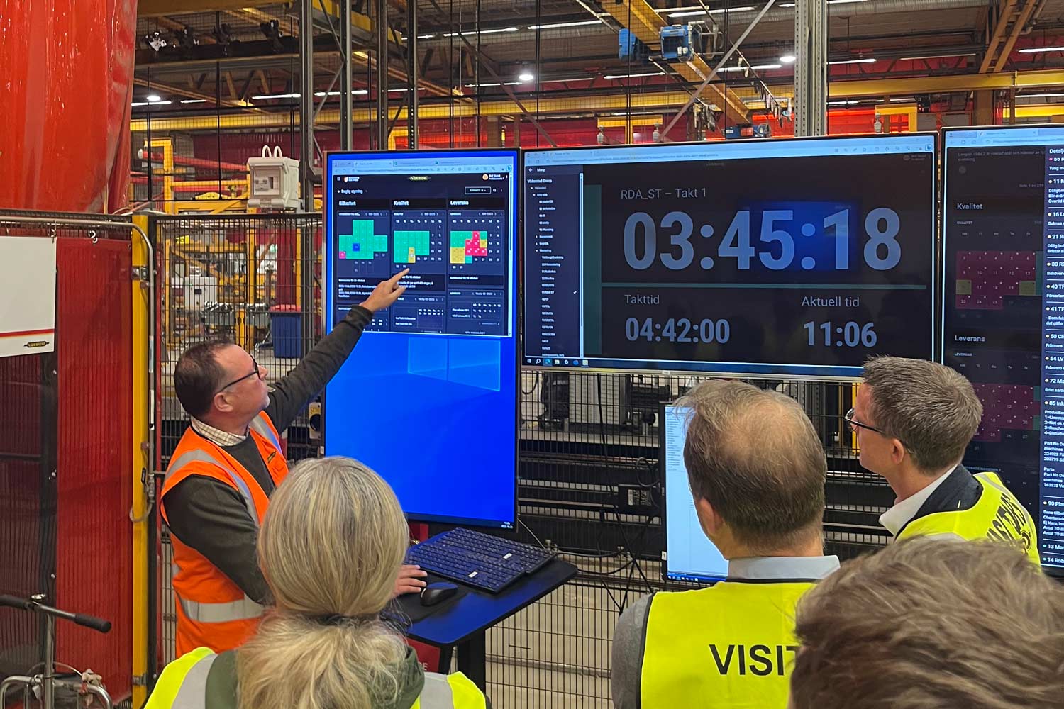 Employees and visitors at Väderstad monitor takt status and production data in Boards on Fire TAKT across several screens.