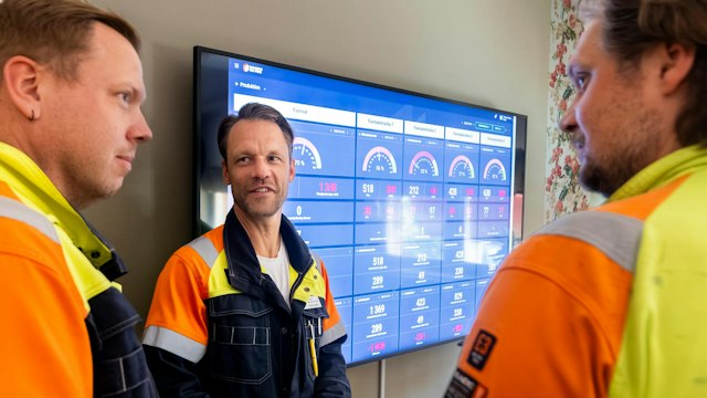 Three SSAB employees standing in front of a Boards on Fire huddleboard