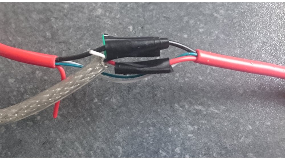 De rode en zwarte draden zijn aan elkaar gesoldeerd en geïsoleerd.