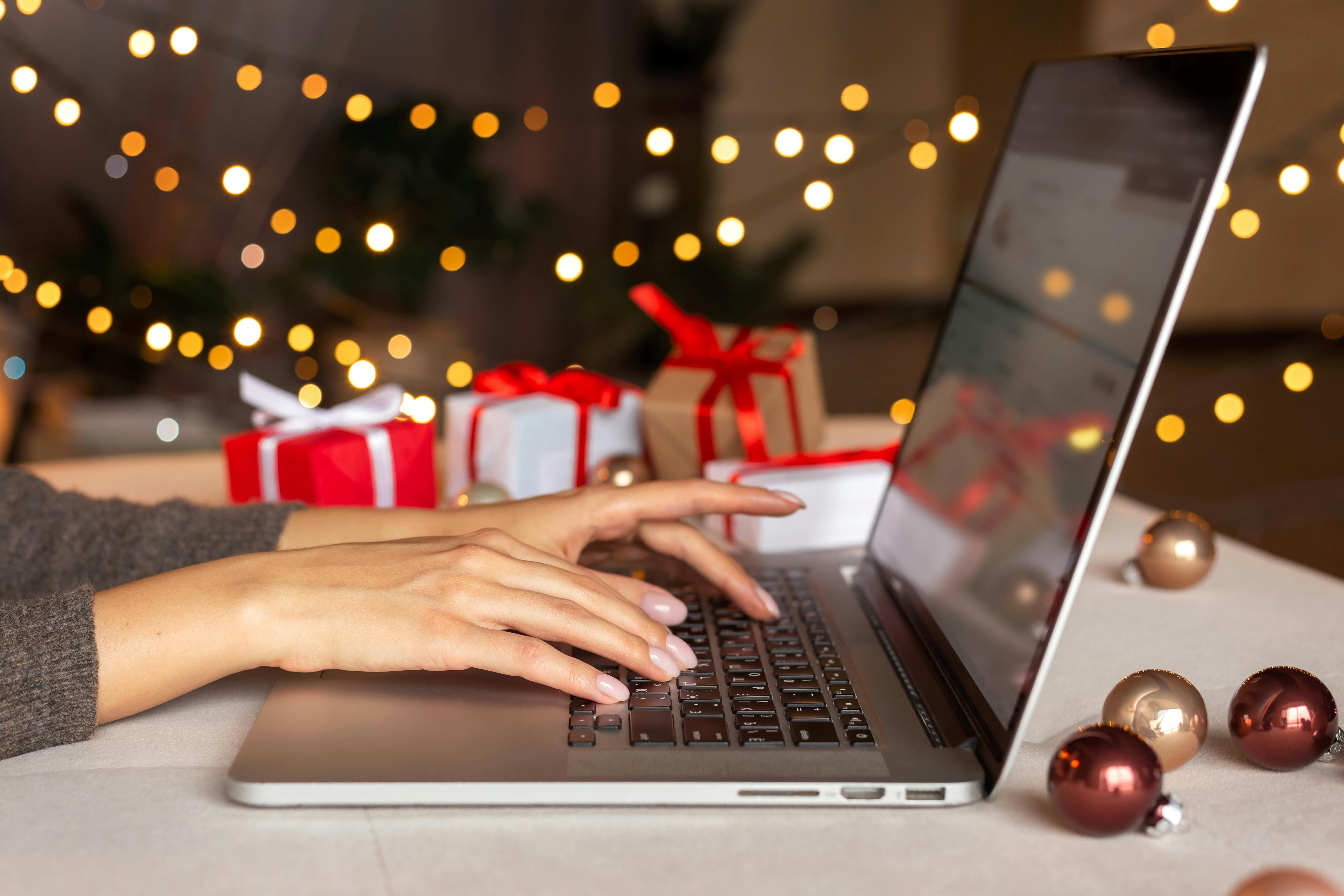 vrouw achter laptop en kerstcadeaus op de achtergrond