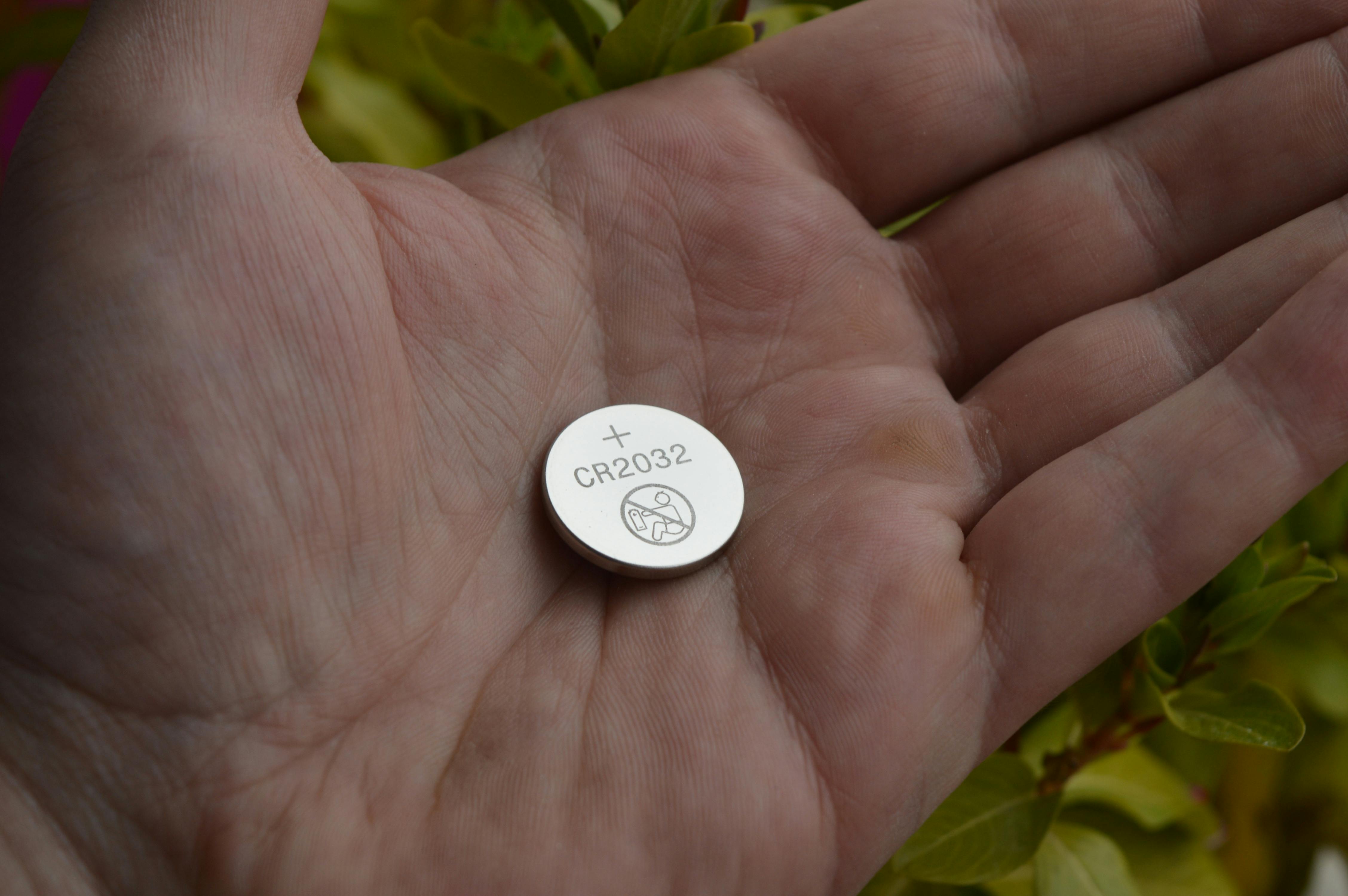 Iemand die een knoopcelbatterij vasthoudt