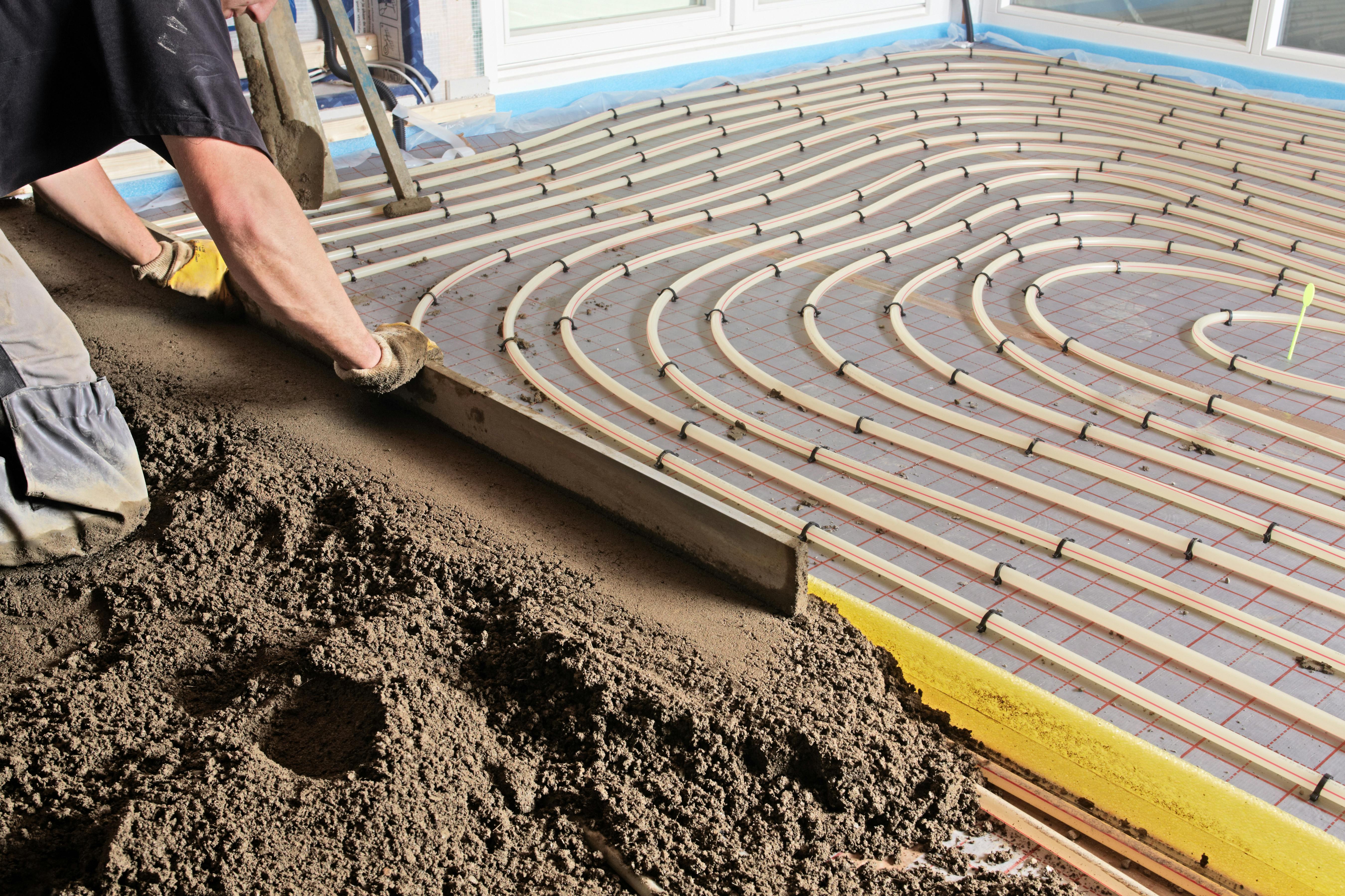 In een nat vloerverwarmingssysteem worden de leidingen bedekt door een vochtig zandcementmengsel.
