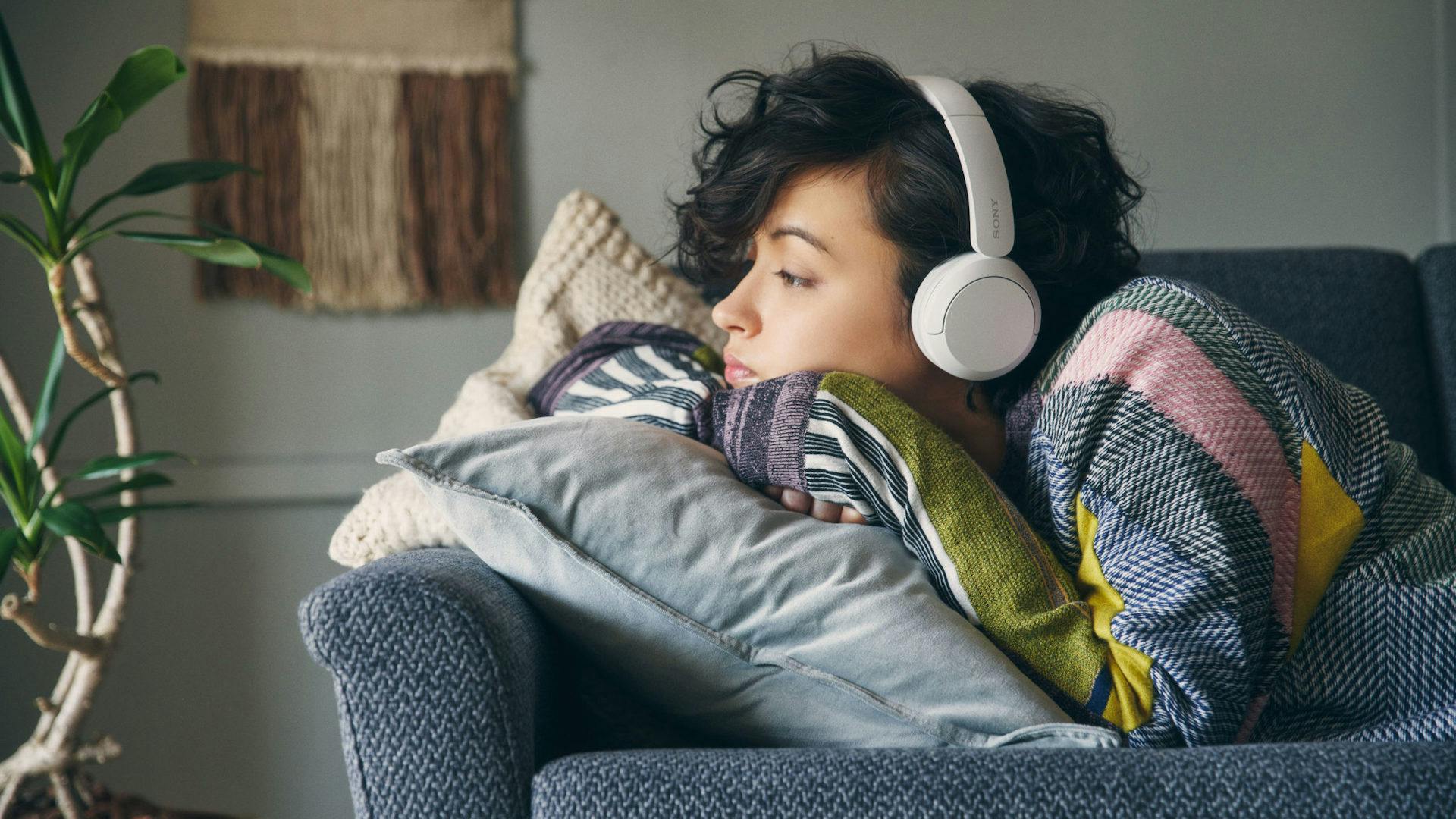 Een vrouw die thuis luistert naar een Sony WH-CH720N koptelefoon