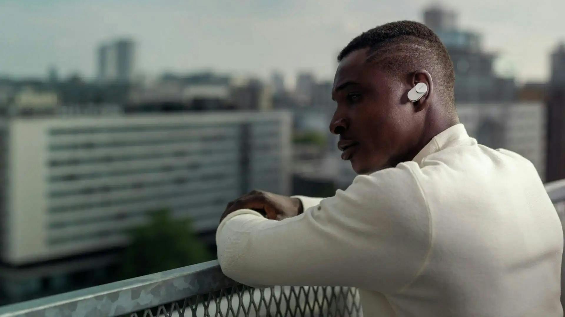 Man met oordoppen kijkt naar een stad.