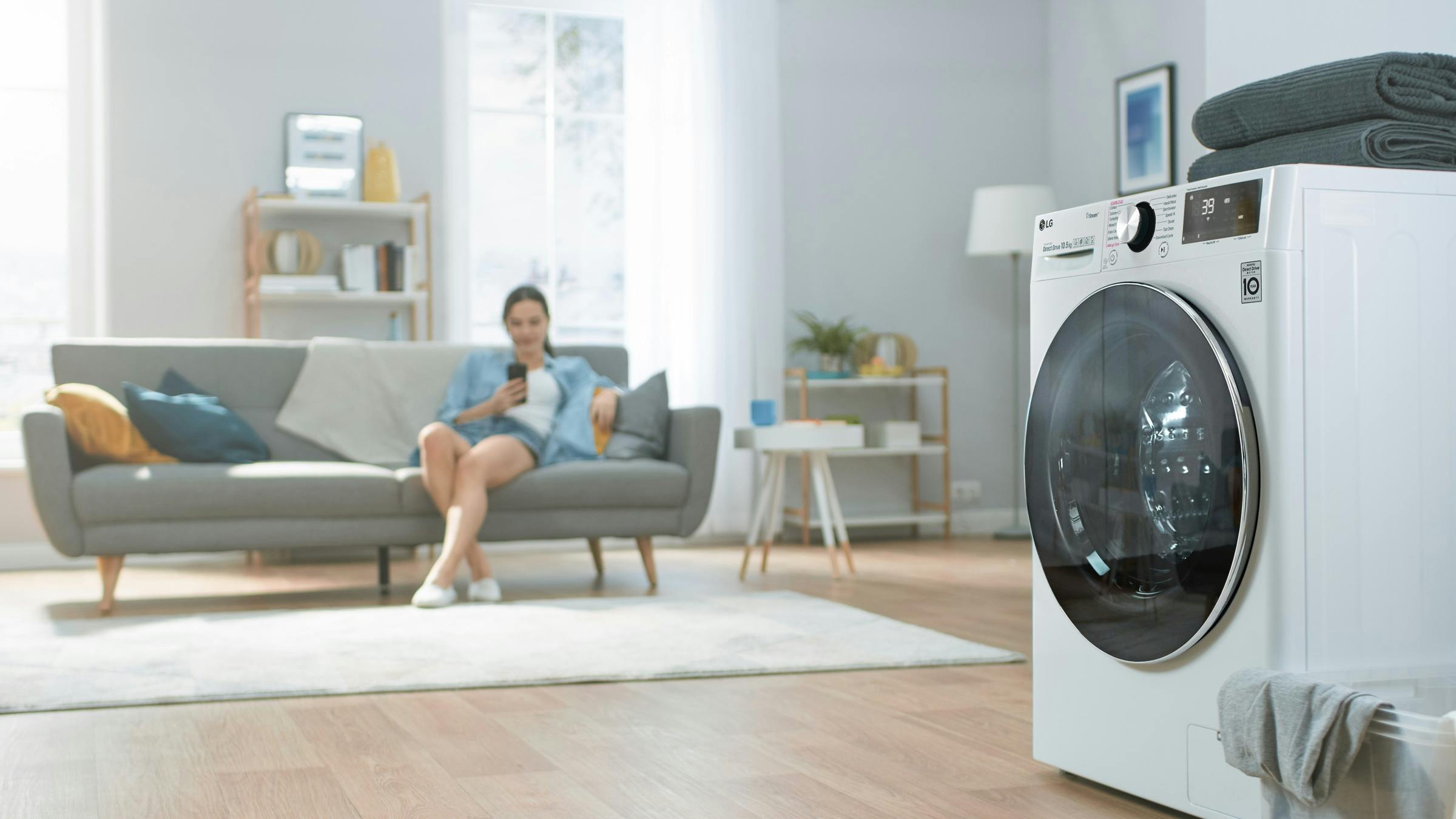 vrouw die kijkt naar telefoon met wasmachine op achtergrond