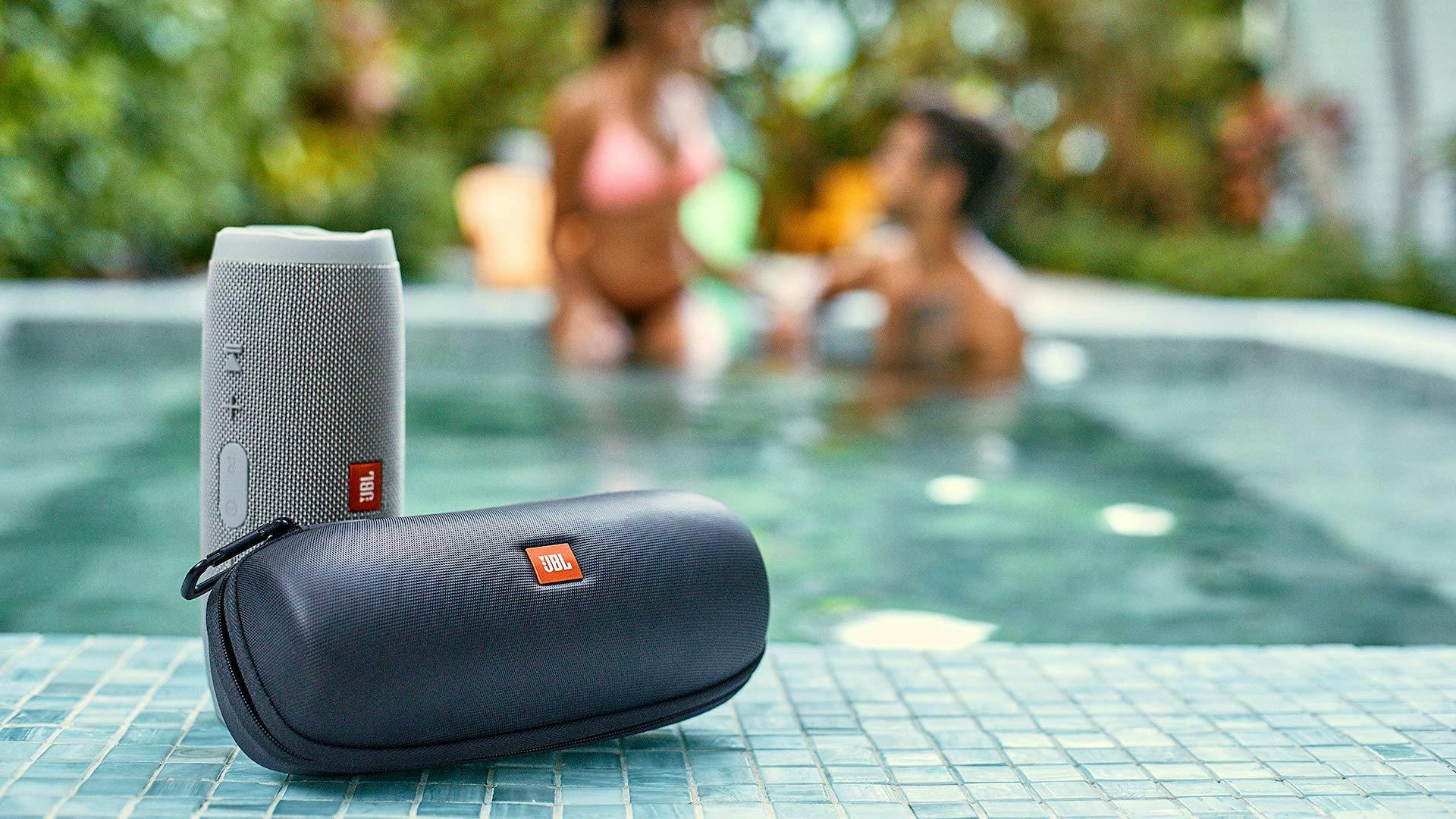 Een waterbestendige Bluetooth-speaker van JBL aan de rand van een zwembad.