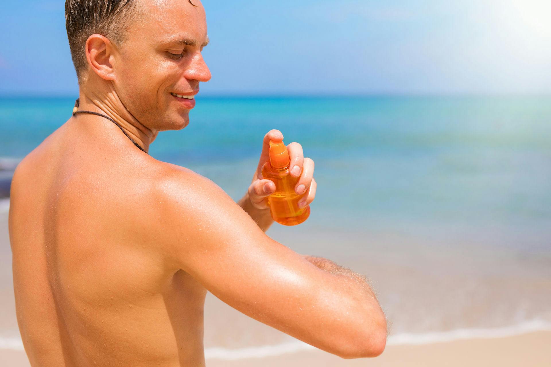 Man met zonnebrandspray