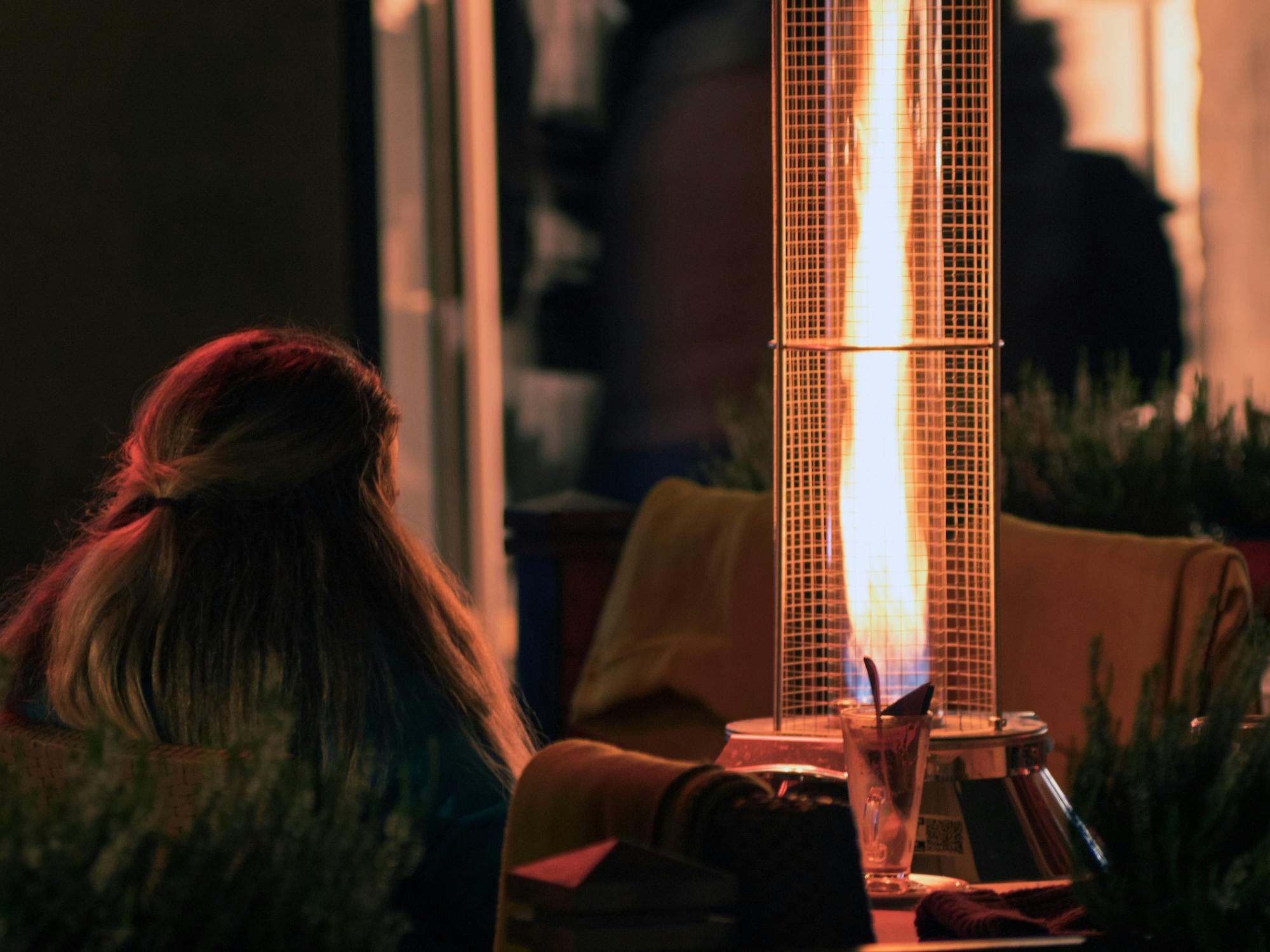 Vrouw zit bij terrasverwarmer