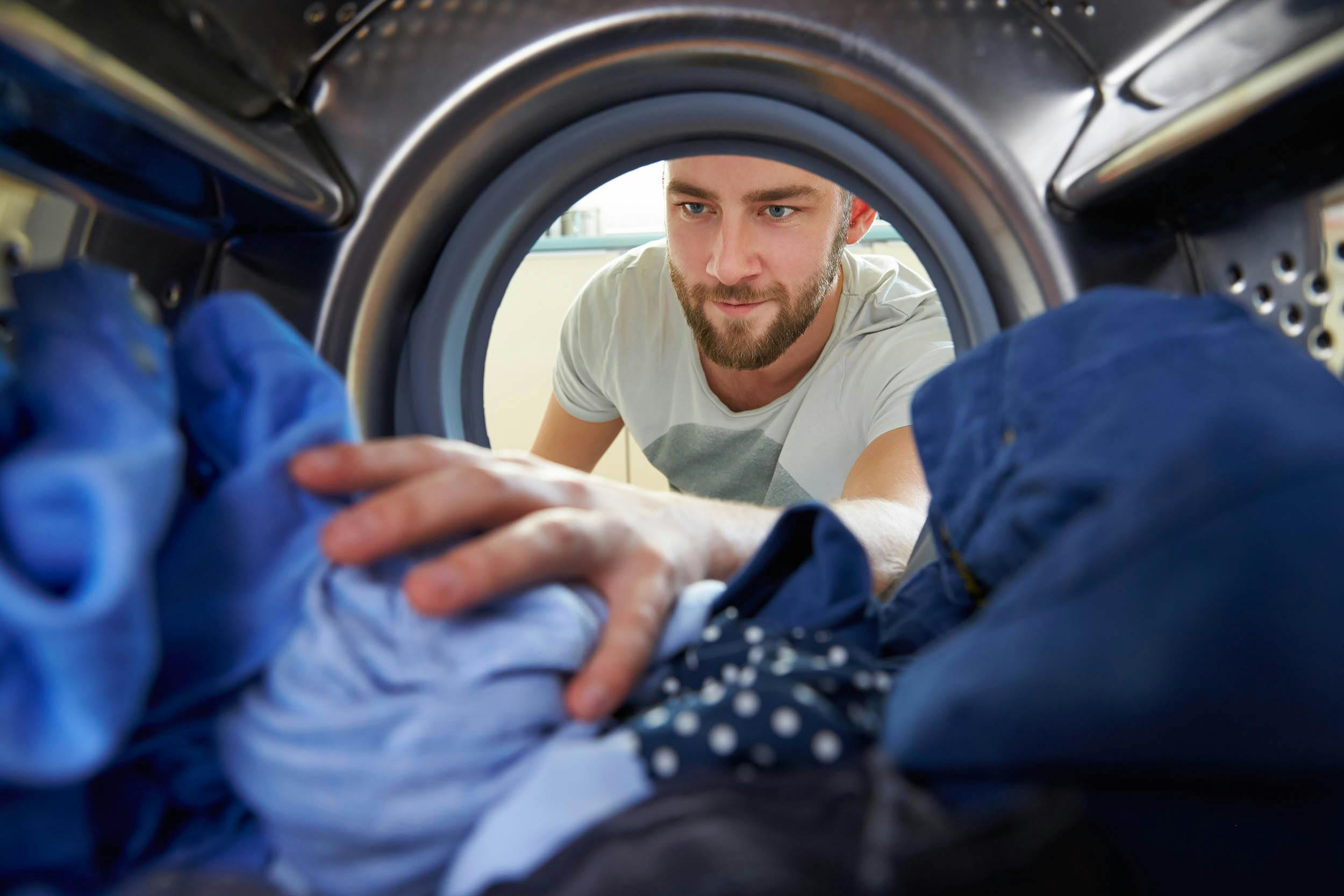 Man die wasgoed in de wasmachine stopt