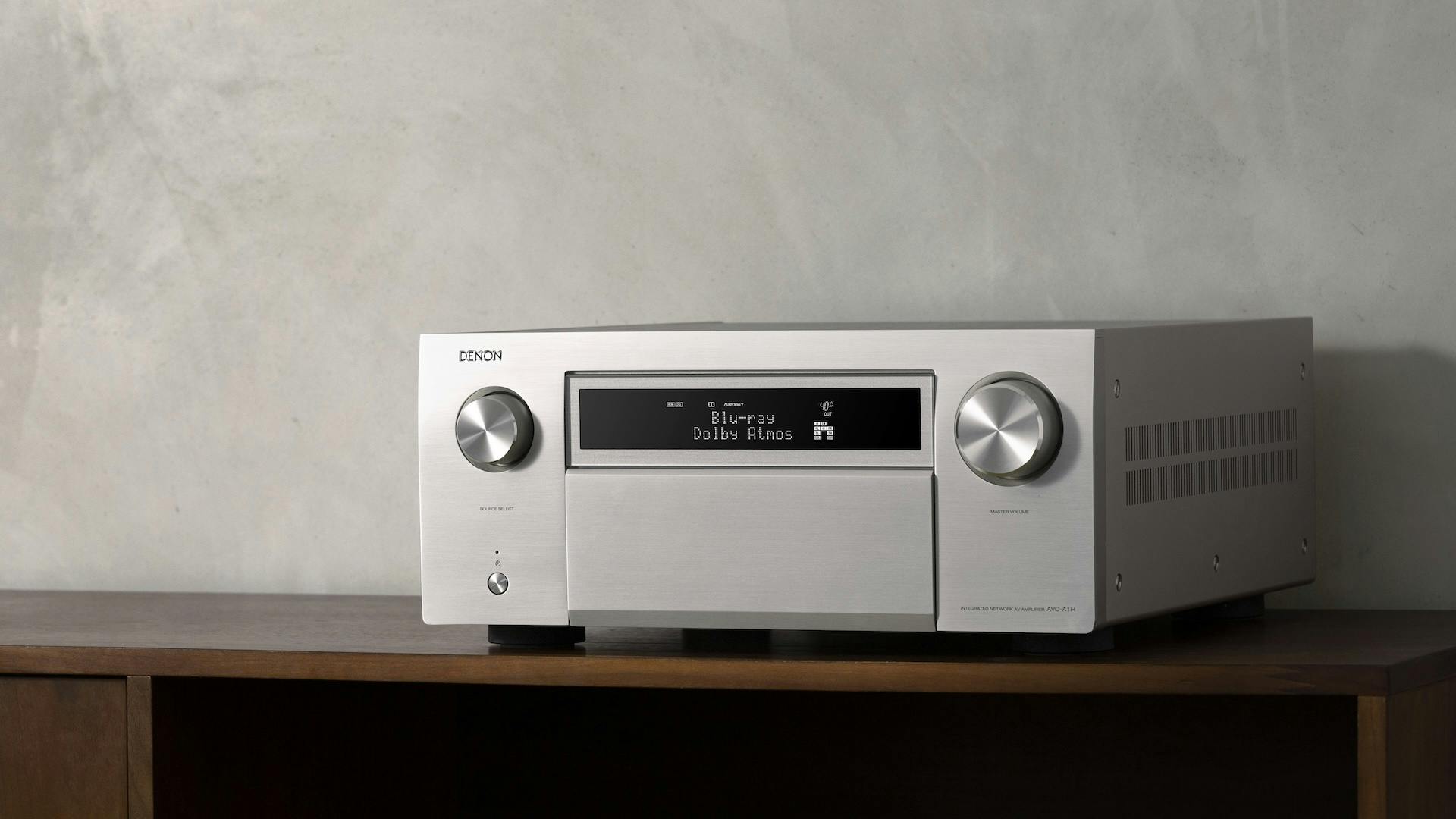 Zilverkleurige Denon AVC-A1H op een kast.