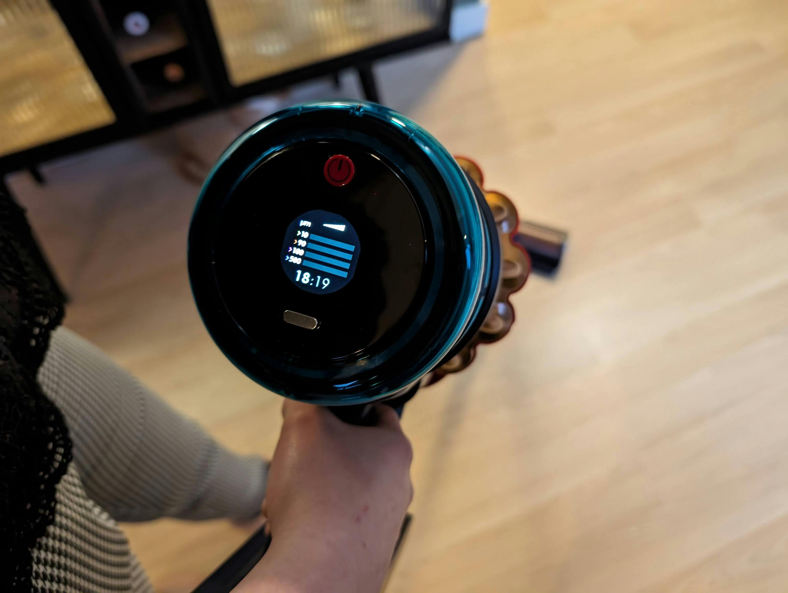 De stofzuiger heeft een aan- en uitknop boven het lcd-scherm.