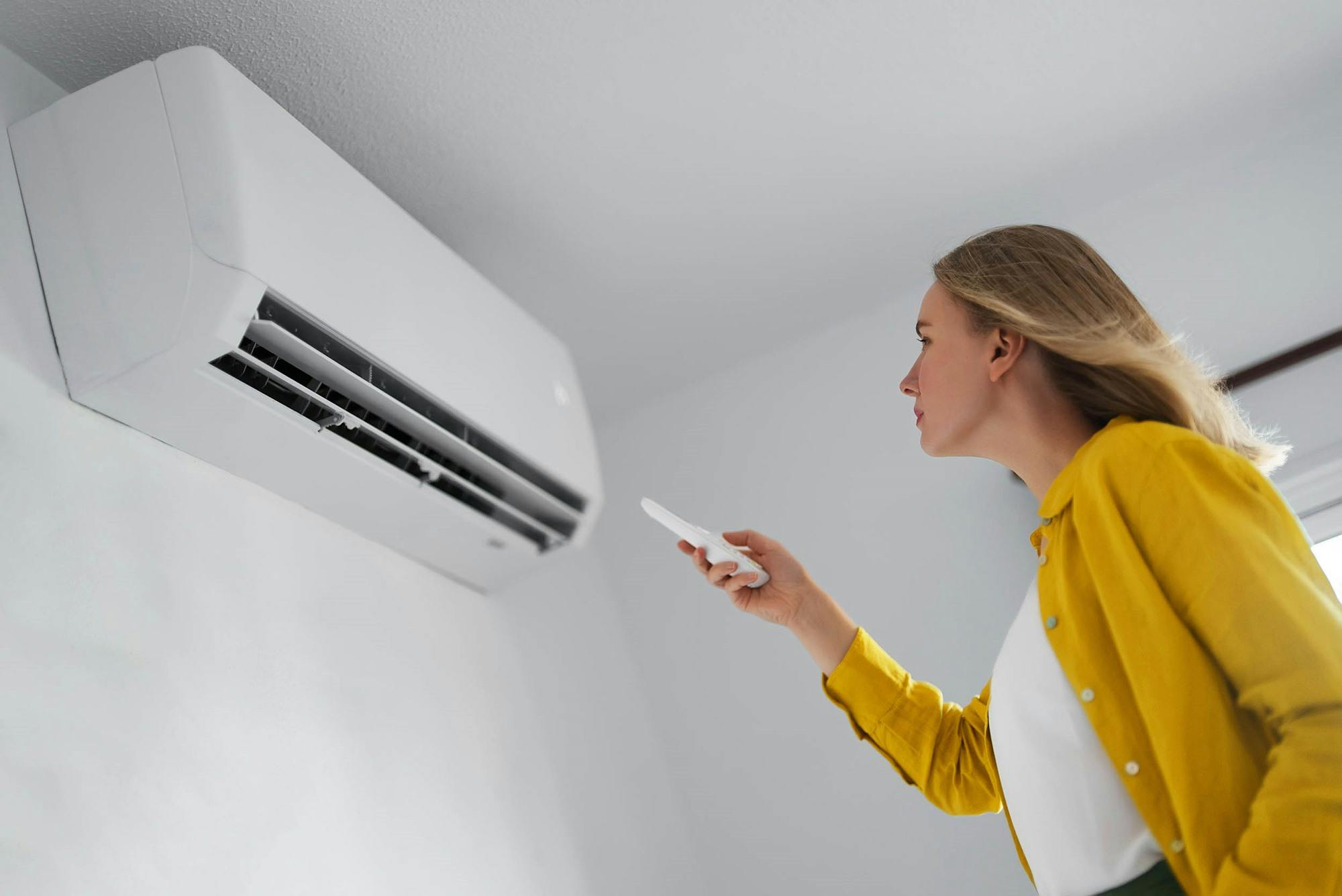 Vrouw die met afstandsbediening airco bedient