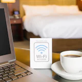 kopje koffie met laptop in een hotelkamer en een free wifi bordje