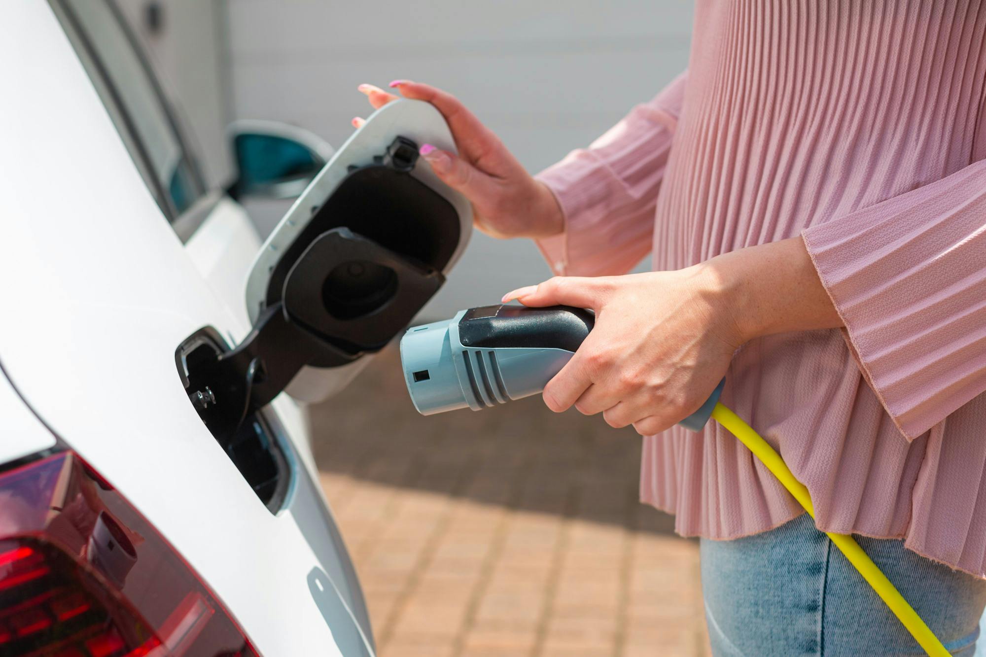 Vrouw sluit laadkabel aan op de auto
