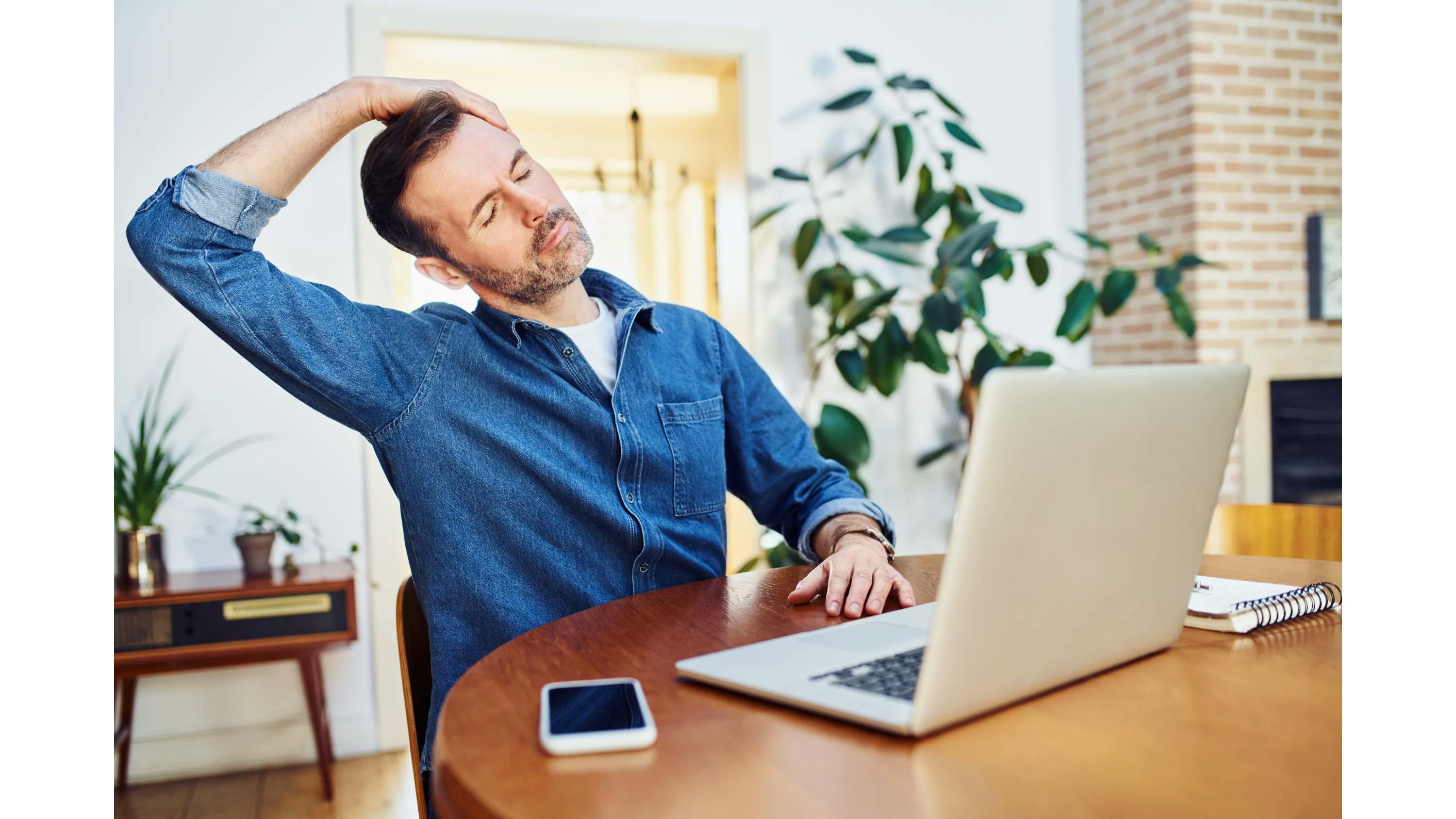 Man met achter laptop op werkplek die oefening doet tegen RSI en KANS