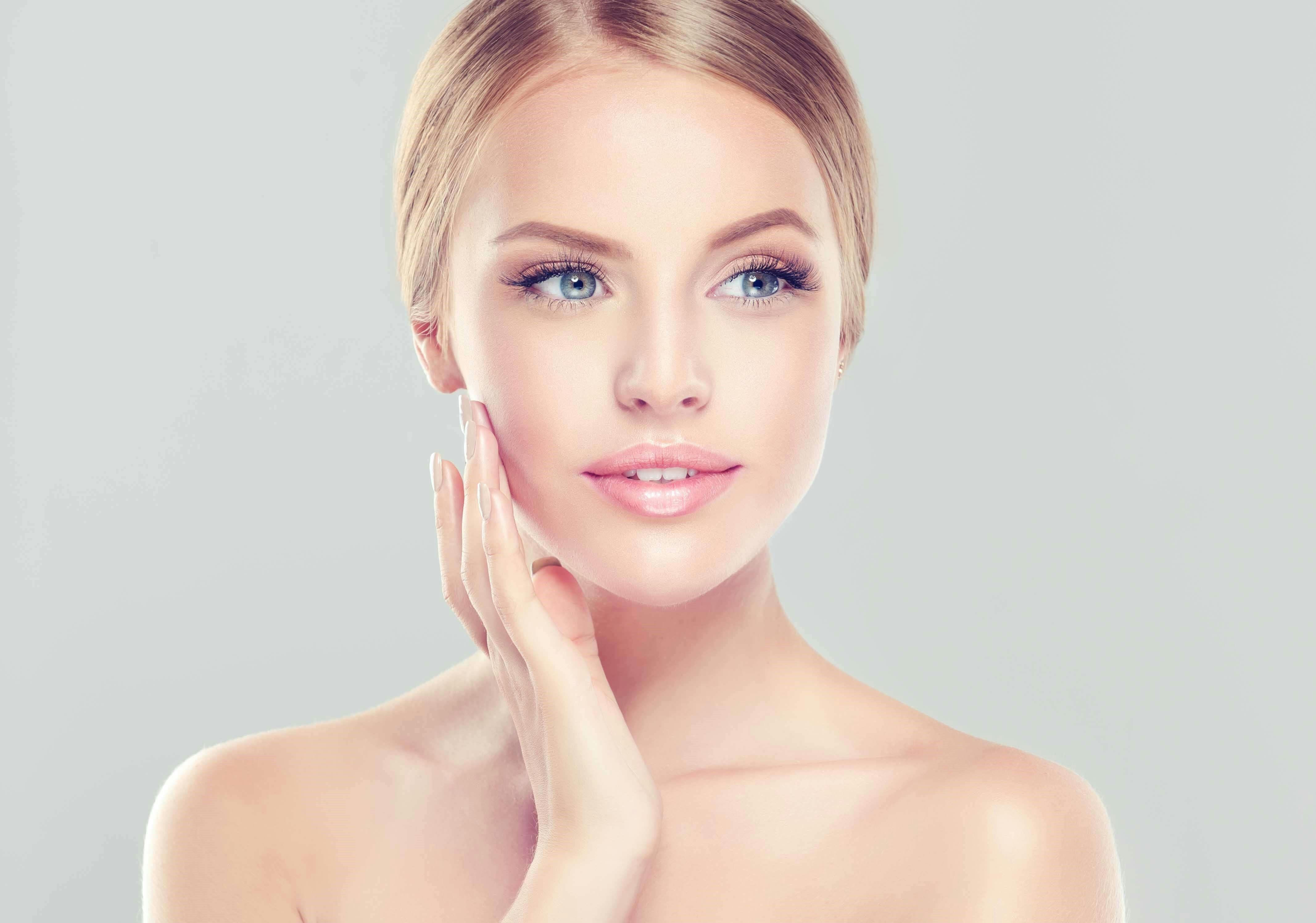Blonde woman touching her cheek
