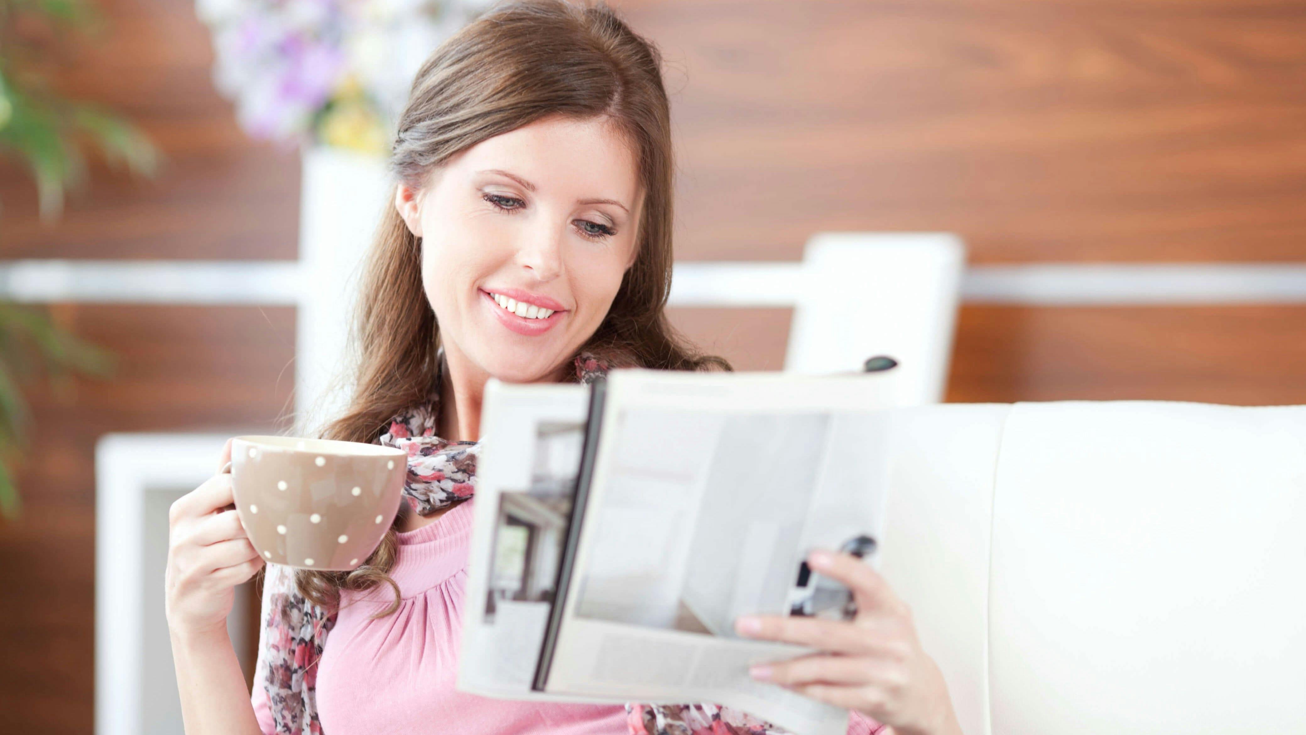 Woman holding a coffe mug reading a paper