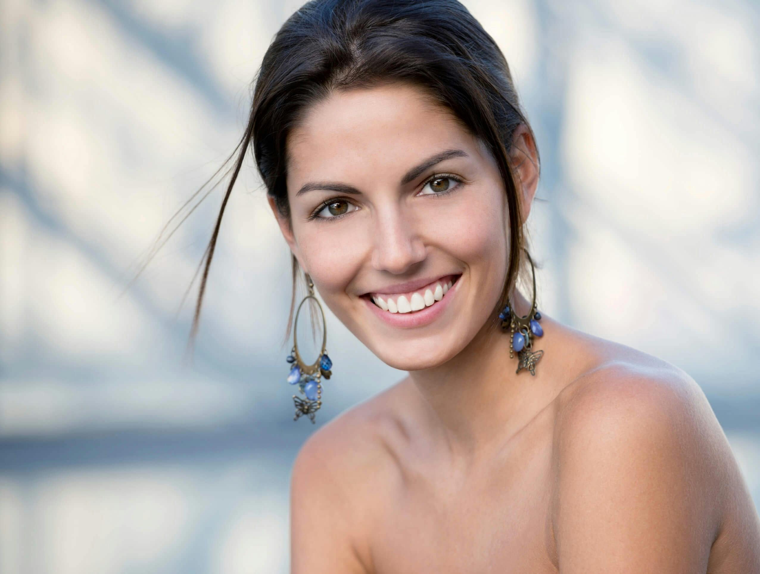 Brunette woman with dangly earrings smiling