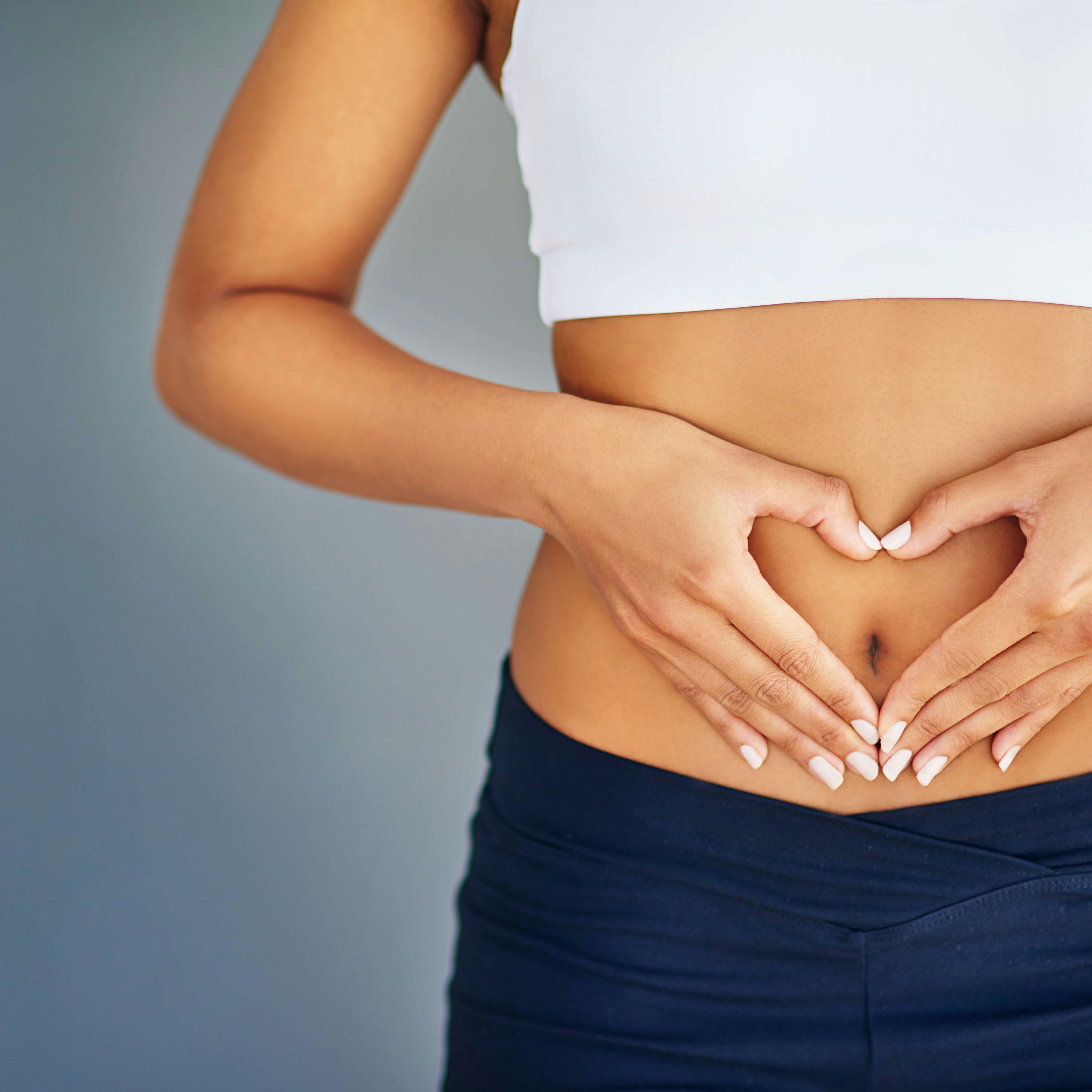 Woman holding hands in shape of heart on her tummy
