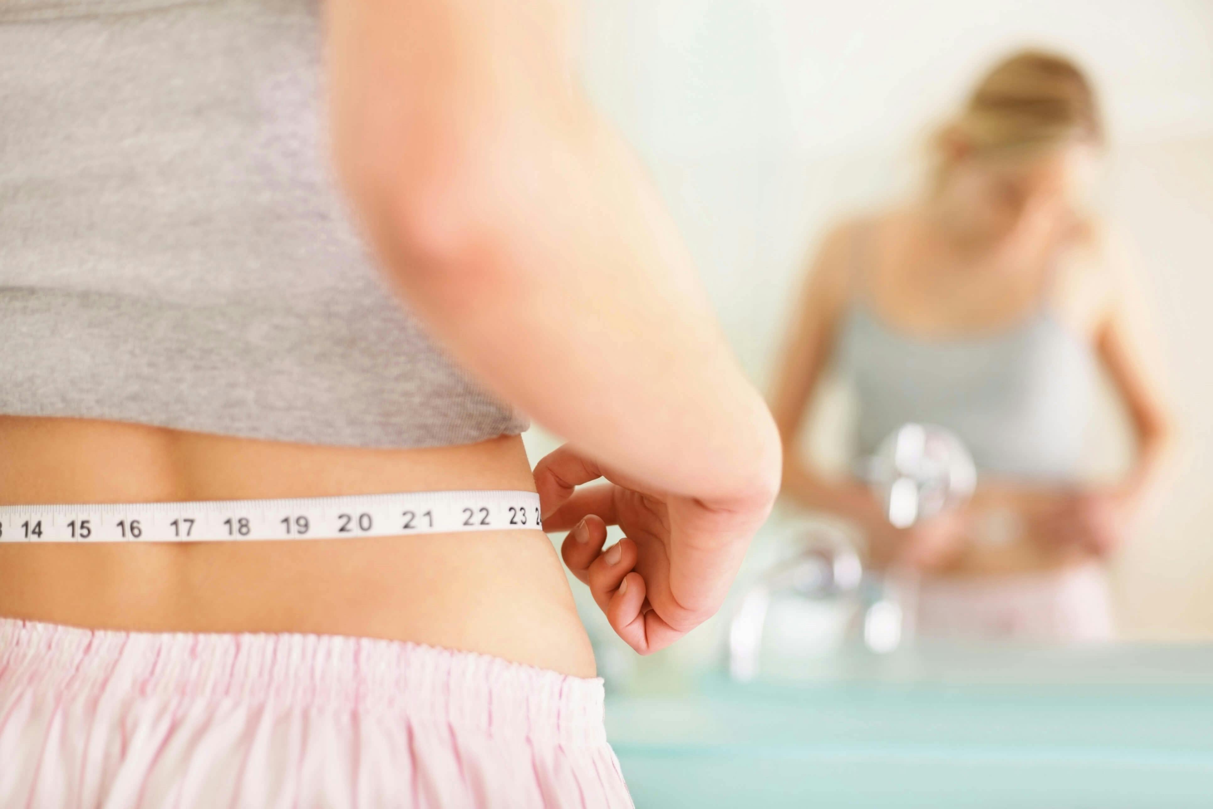 Woman holding tape measure around her waist