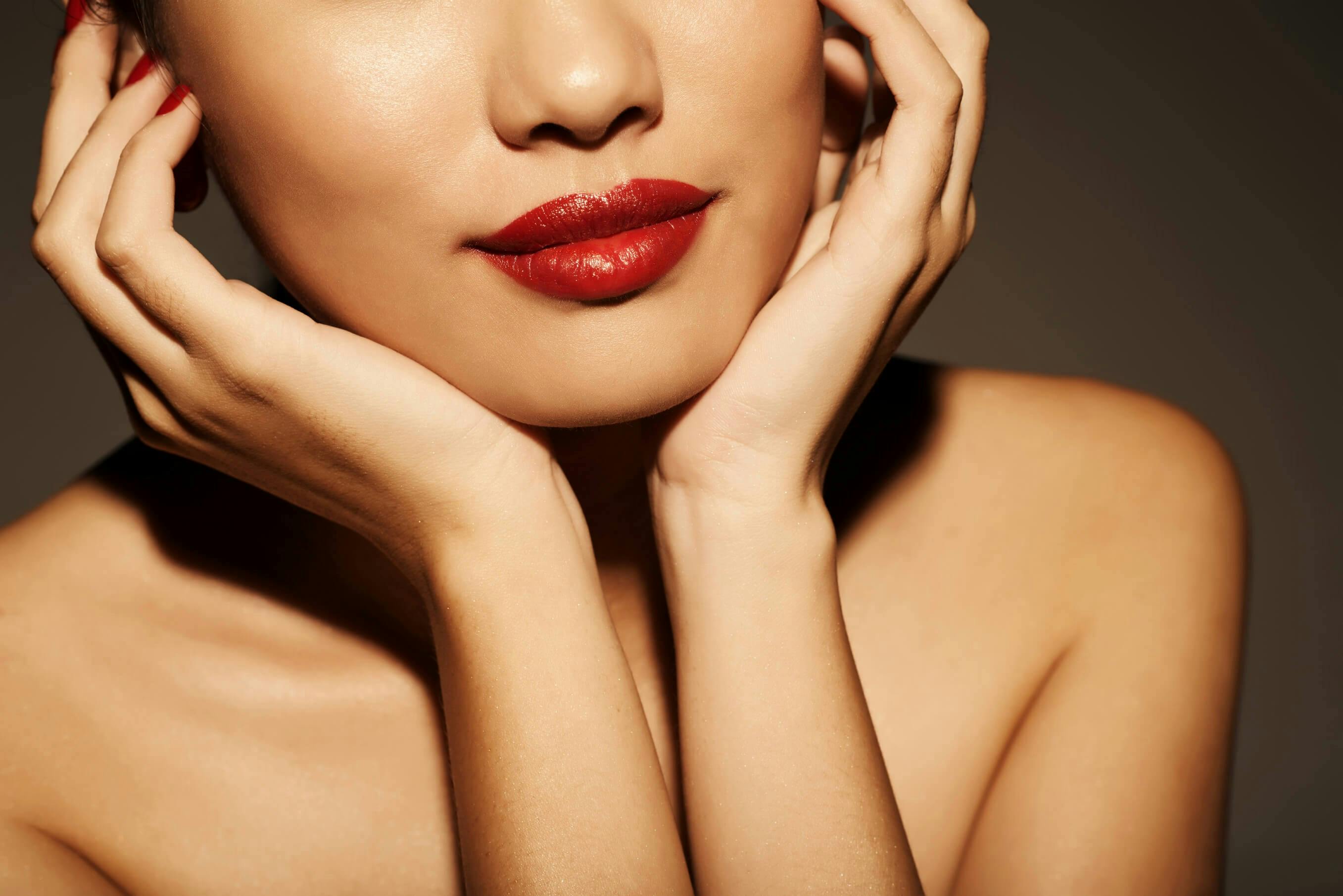 Woman with red lipstick holding face in her hands
