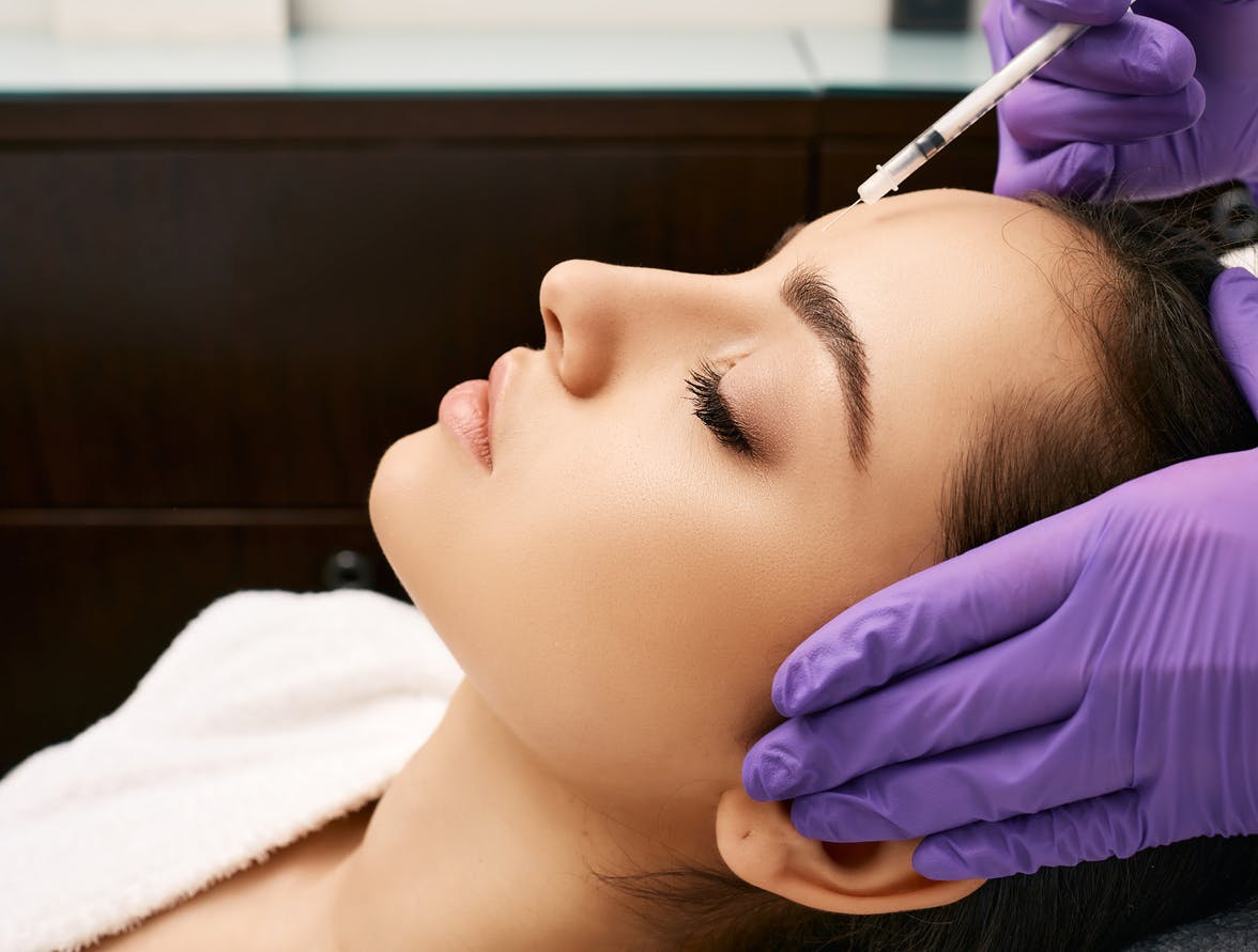 Woman getting injection in her forehead. 