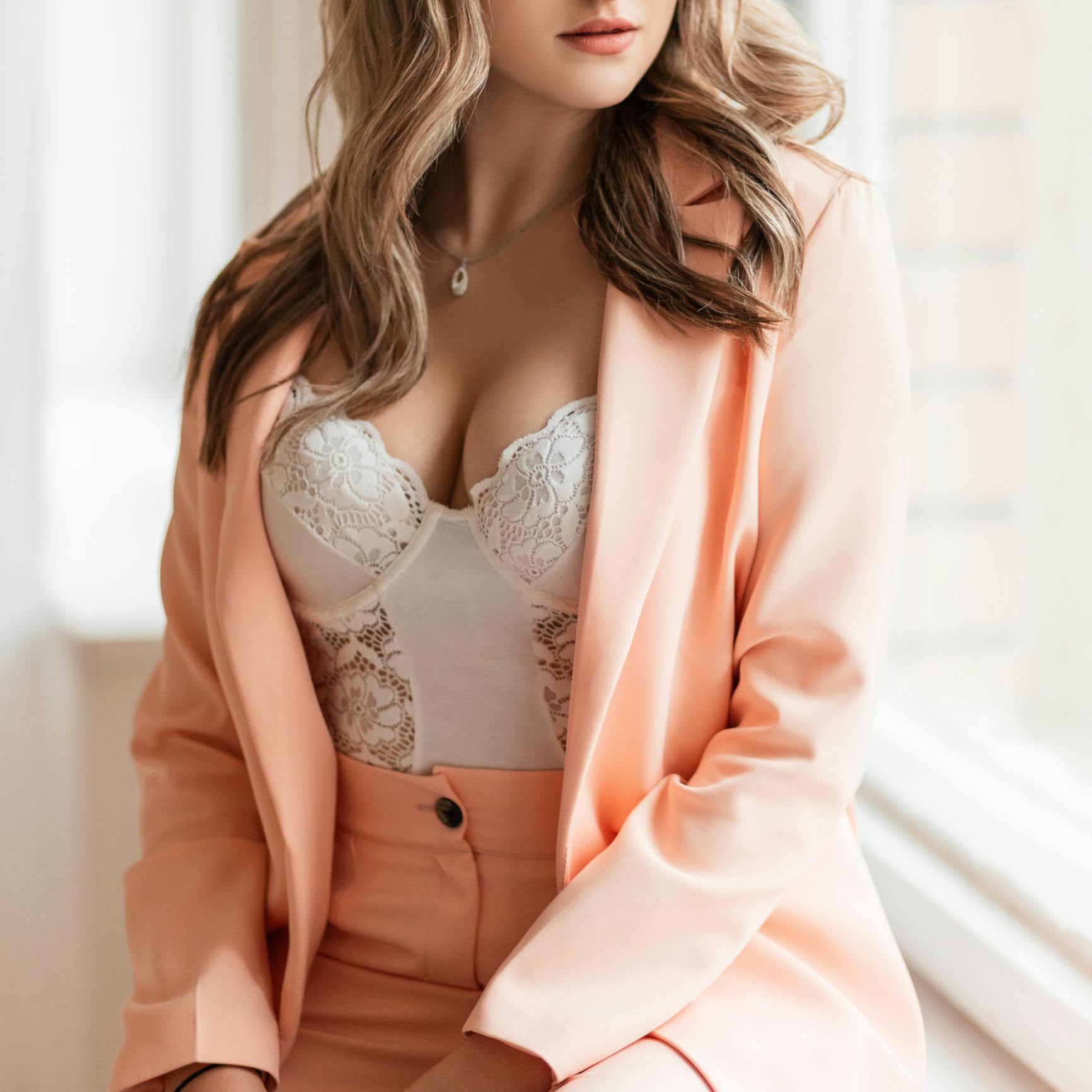Close up of woman's chest in white corset and pink blazer