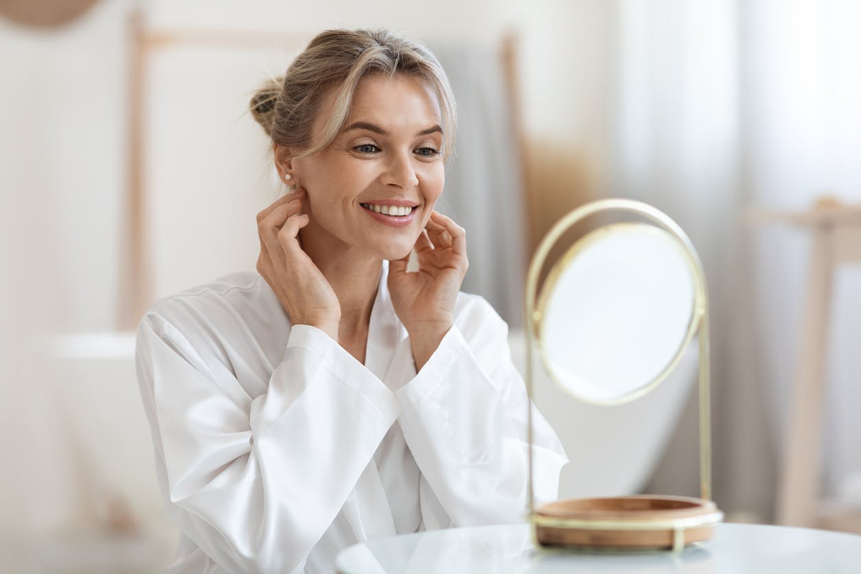 Woman looking in a small mirror smiling